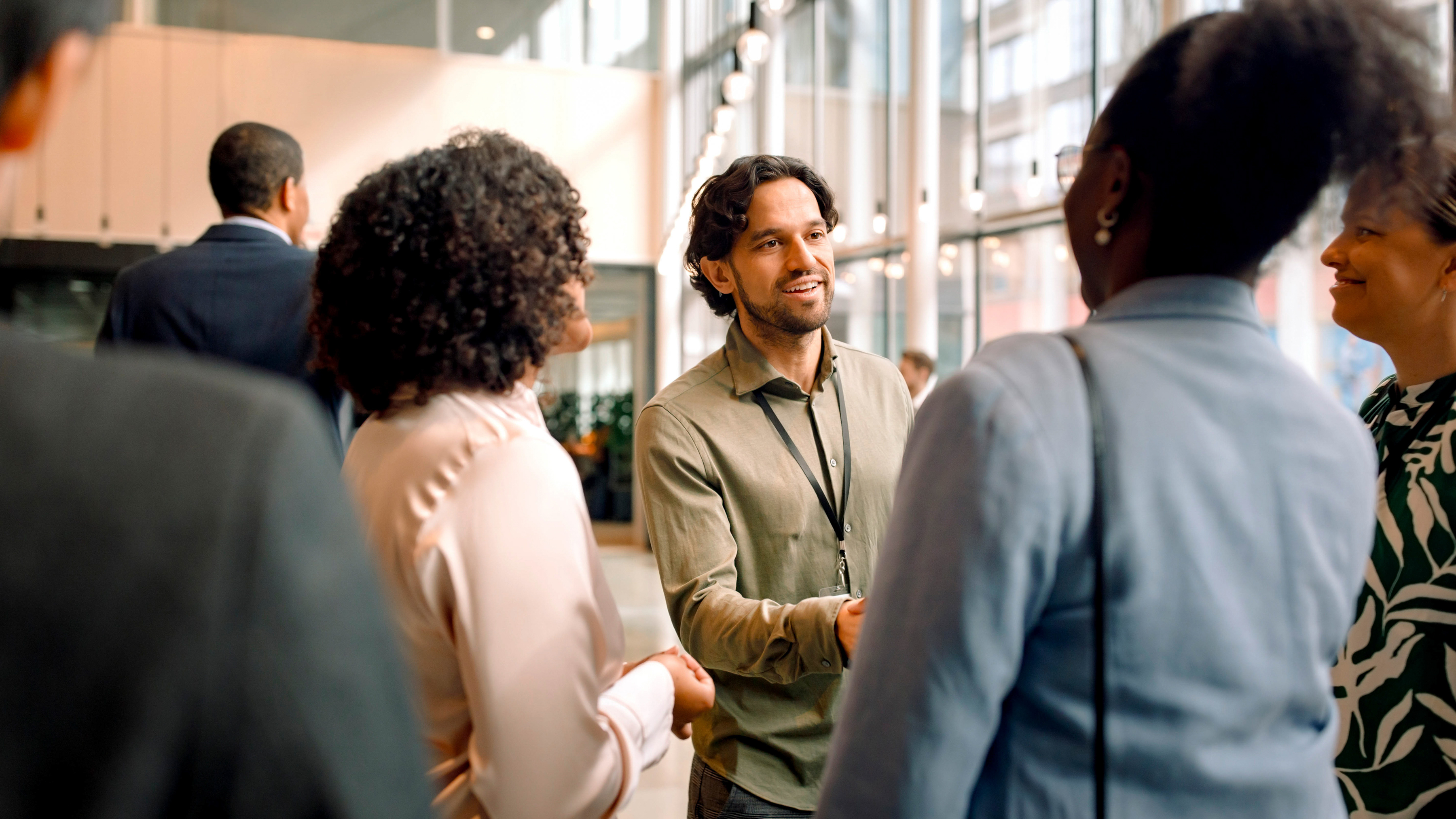 A group of professionals are meeting one another and exchanging handshakes at a conference center.