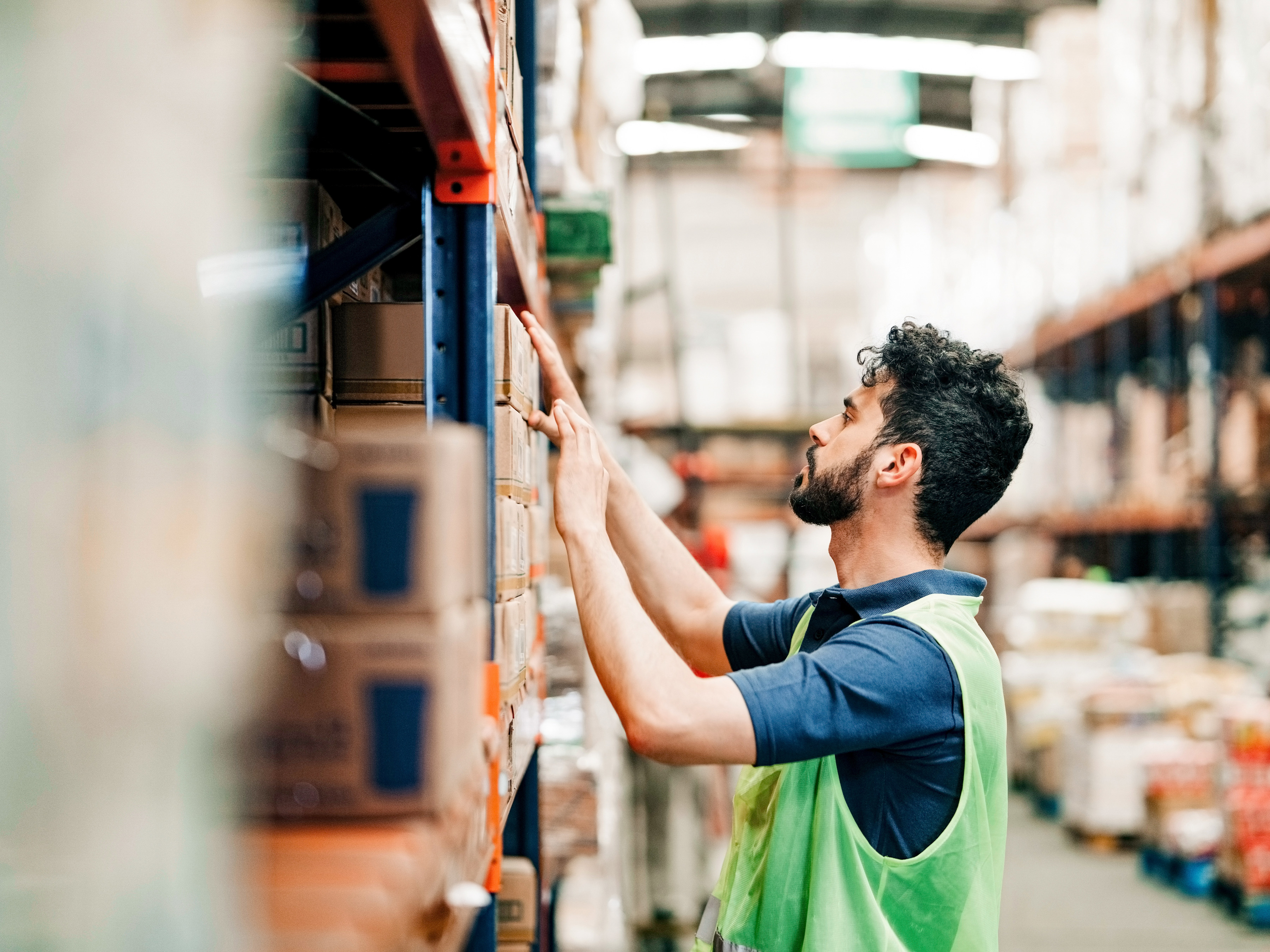 A worker is checking inventory on a shelf in a warehouse.