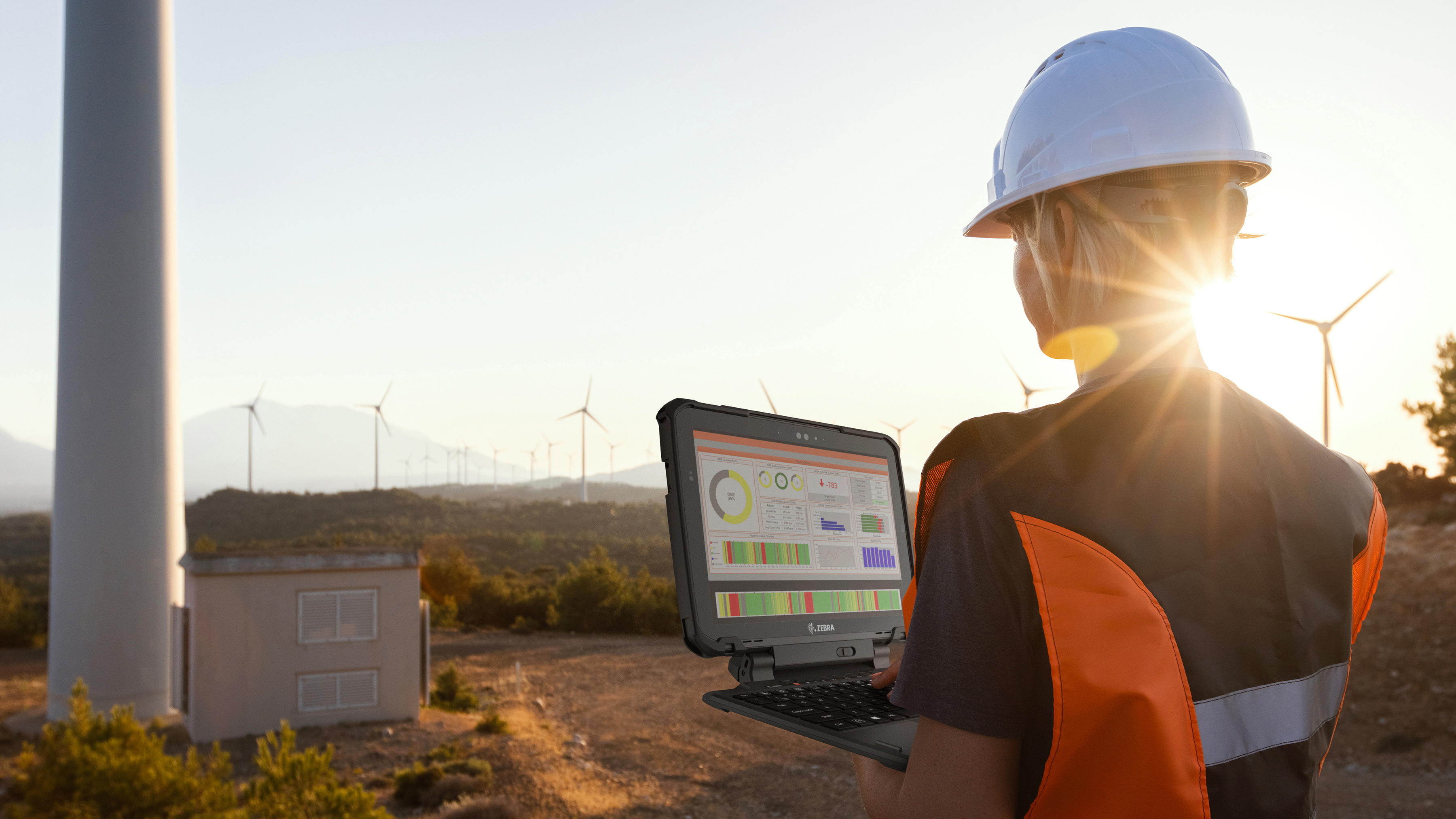 An engineer using a laptop during a wind power field inspection.