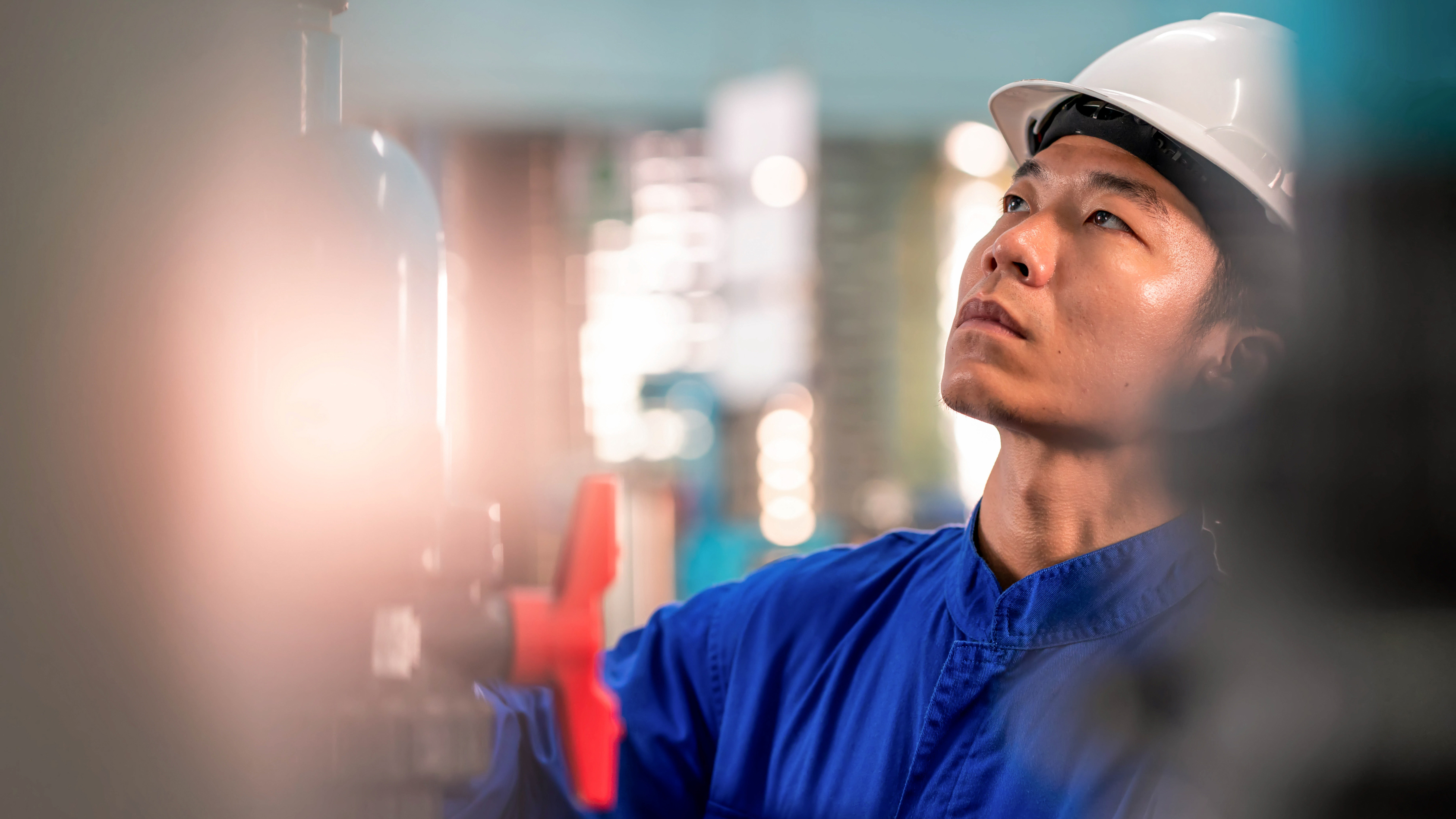 An industrial worker examining equipment for maintenance.