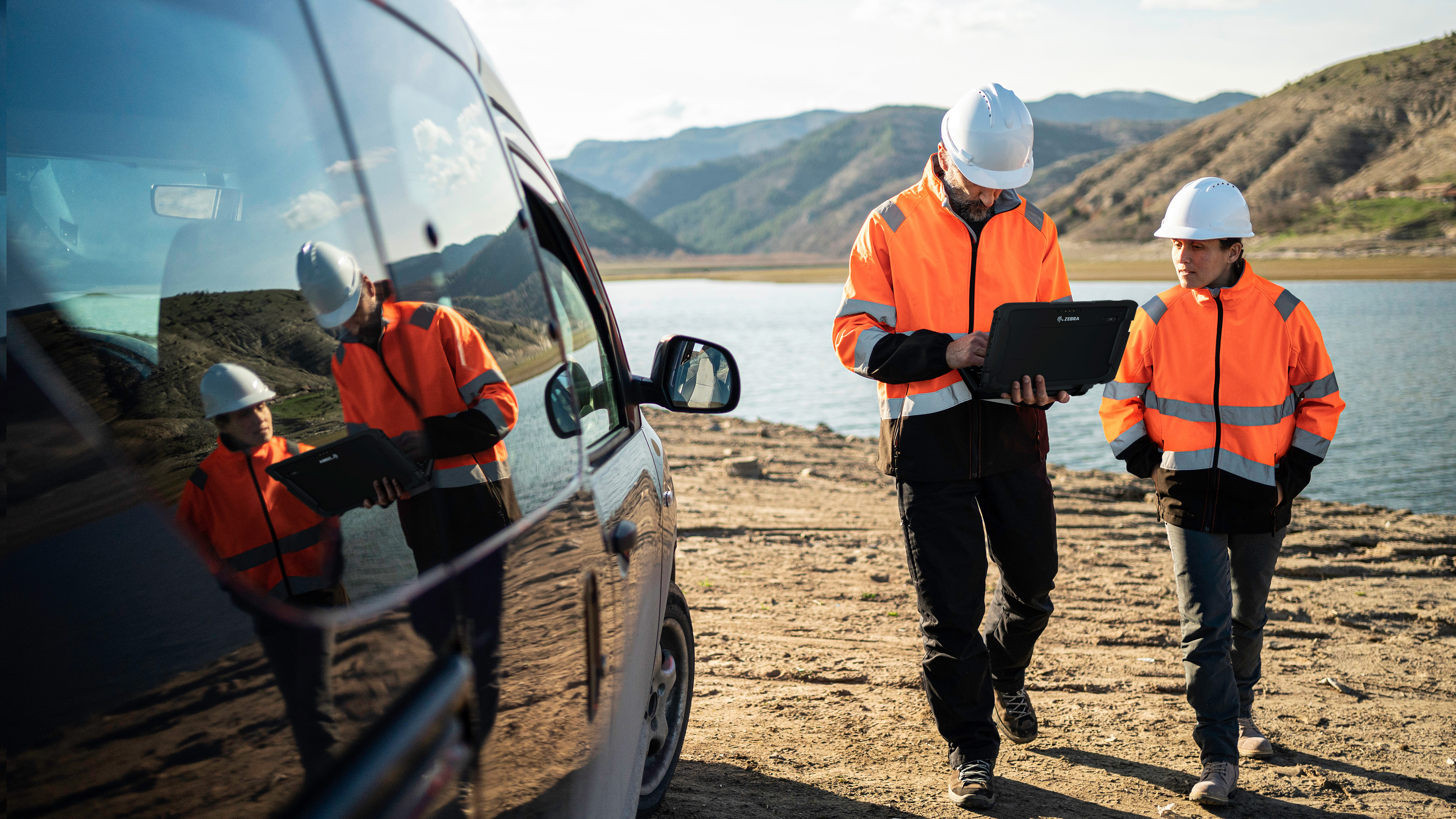 Engineer walking outdoors near water with a Zebra tablet.