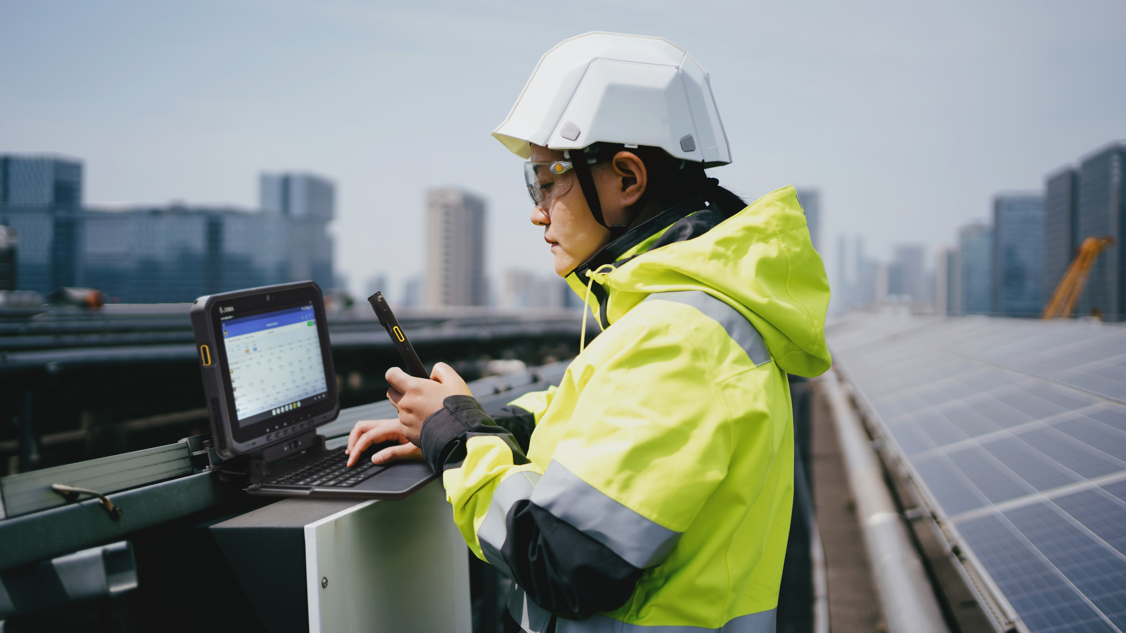 Worker using a Zebra handheld mobile computer and a Zebra tablet while at  solar power station.