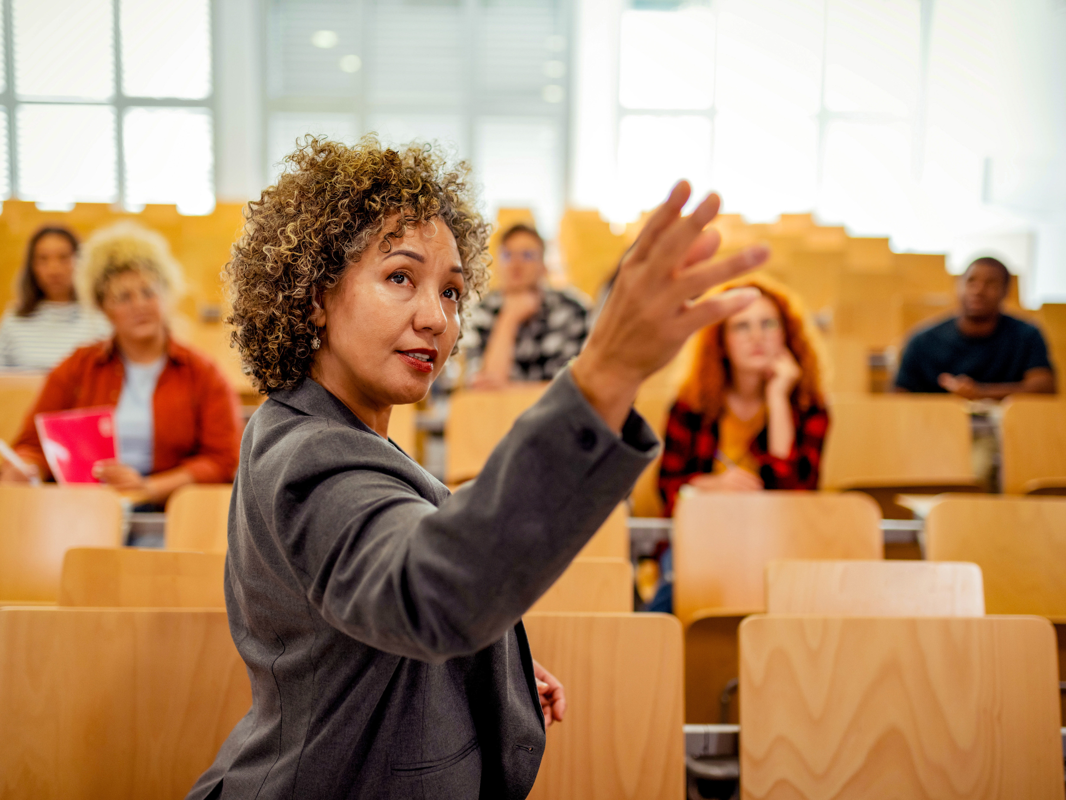 A woman giving a lecture inside a classroom with five students.