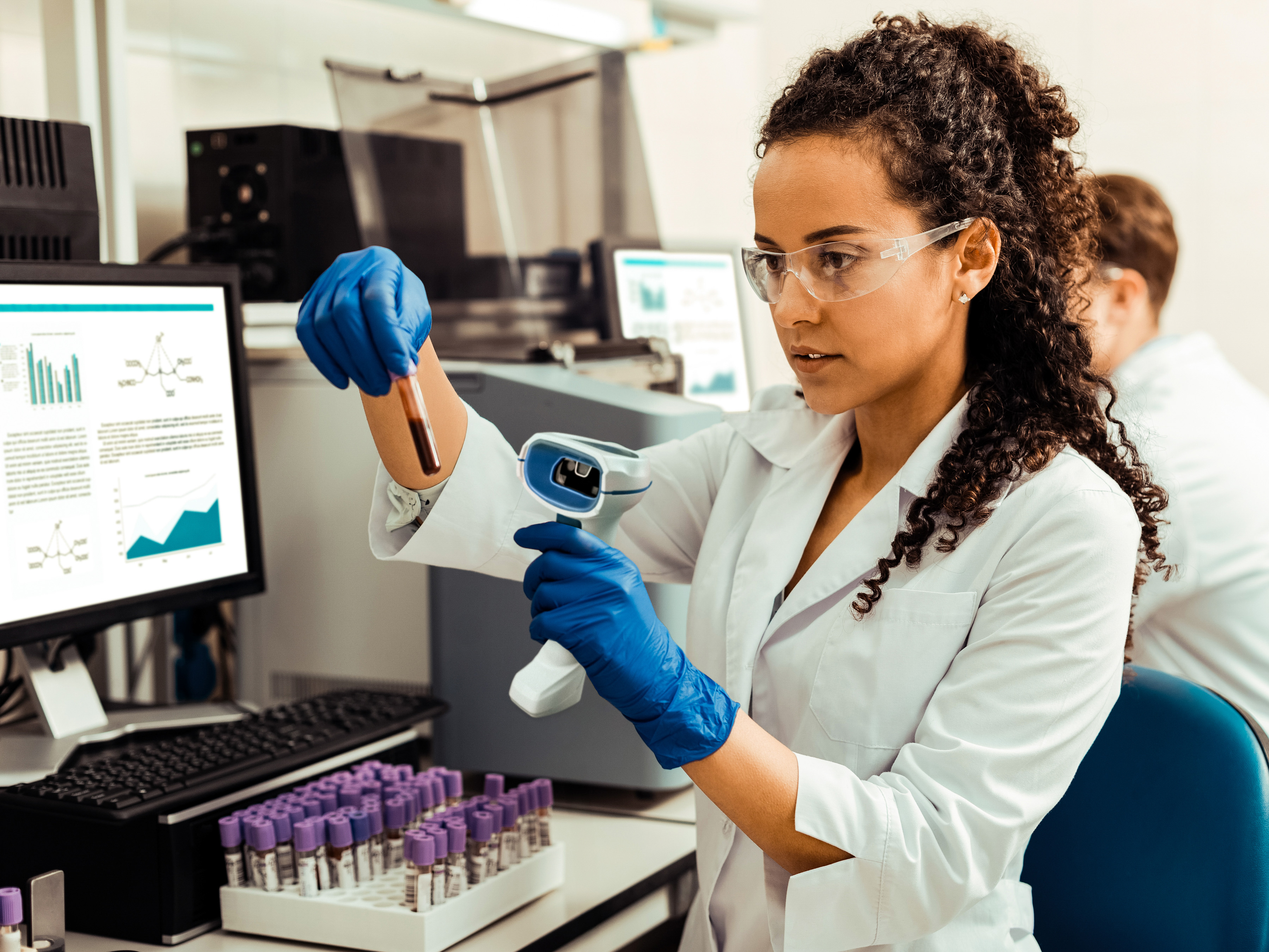 A medical professional uses a Zebra handheld barcode scanner to scan a label on a blood sample.