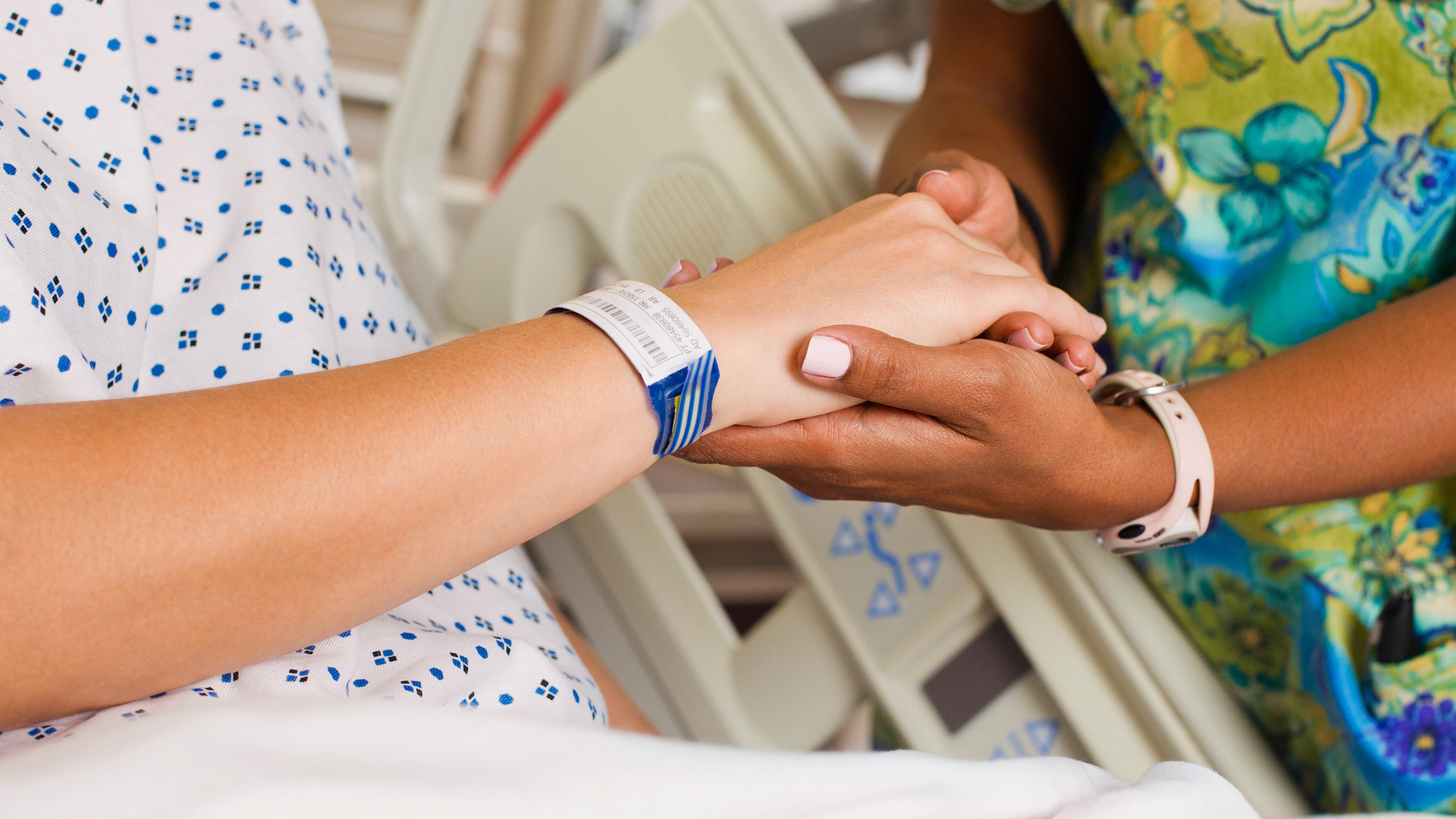 A medical professional inspecting a patient's barcode wristband inside of a hospital.