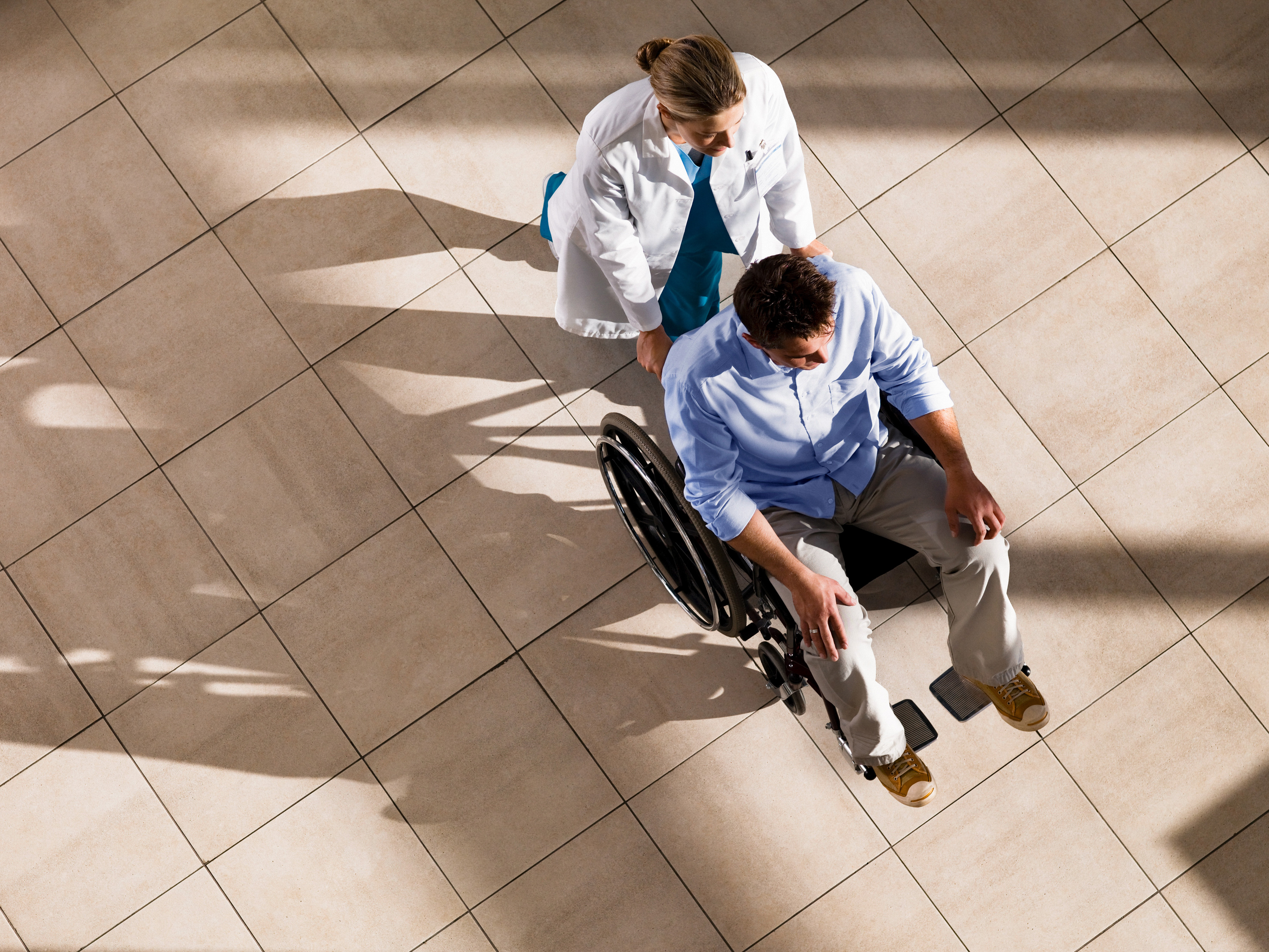 Medical professional pushing a patient in a wheelchair.