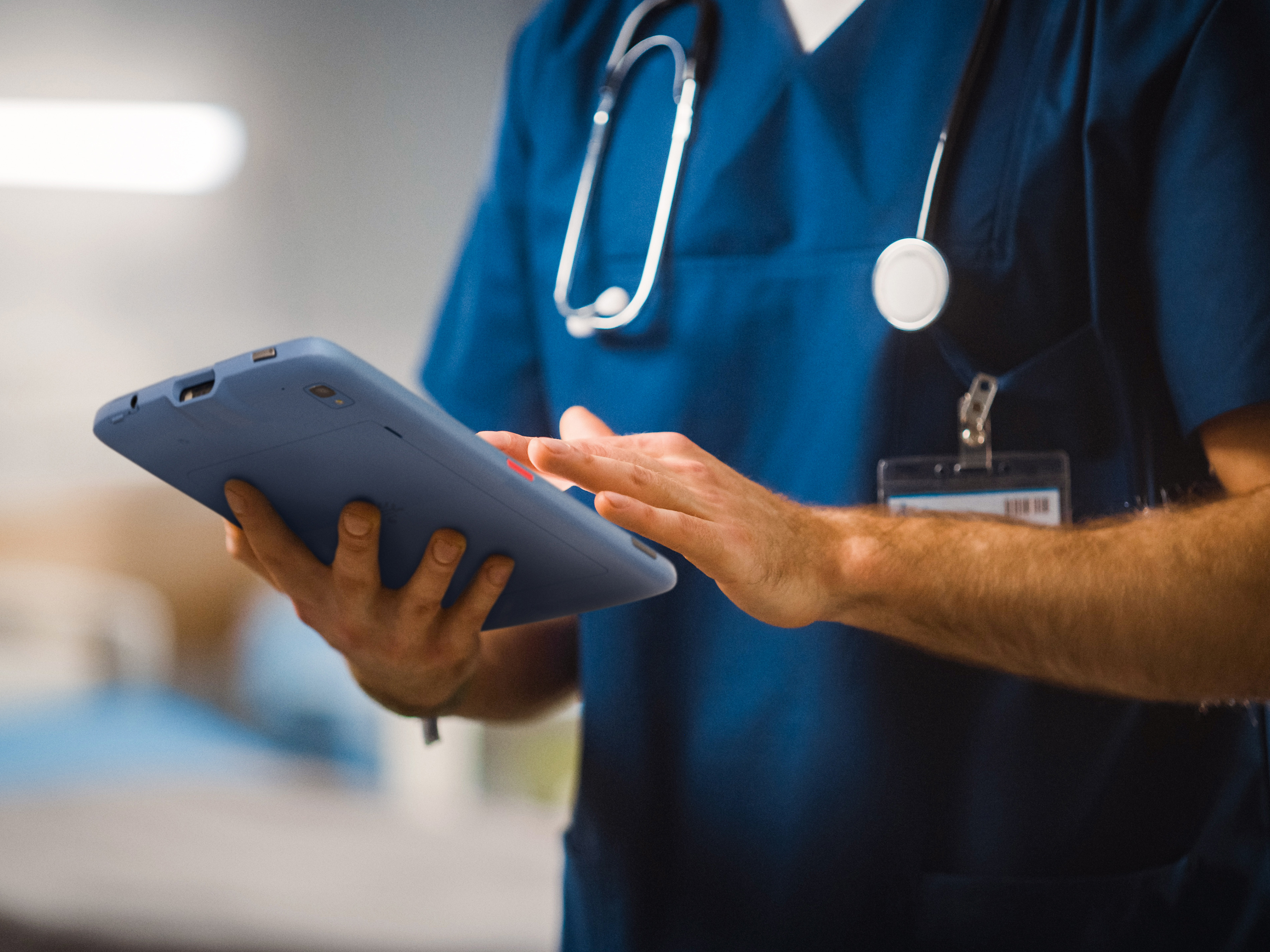 A medical professional using a Zebra tablet inside of a hospital.