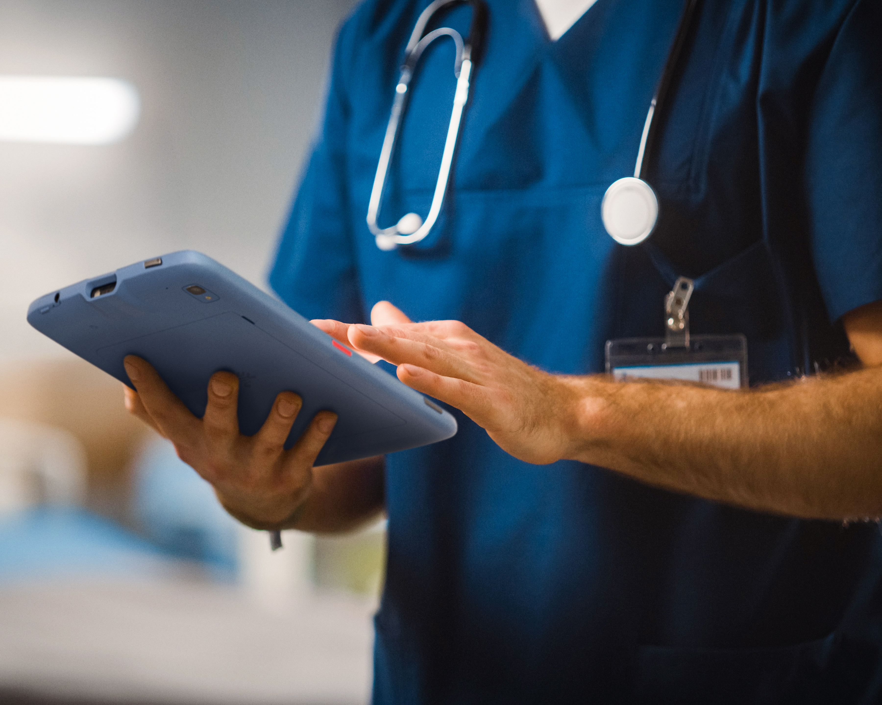 A medical professional using a Zebra tablet inside of a hospital.