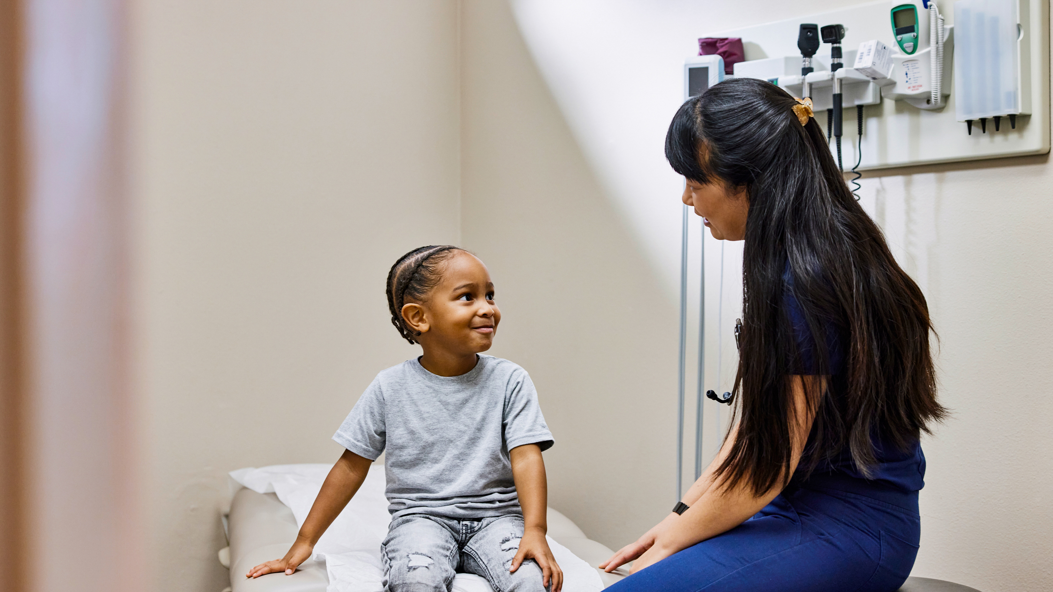 Medical professional talking to a young patient in a hospital room.