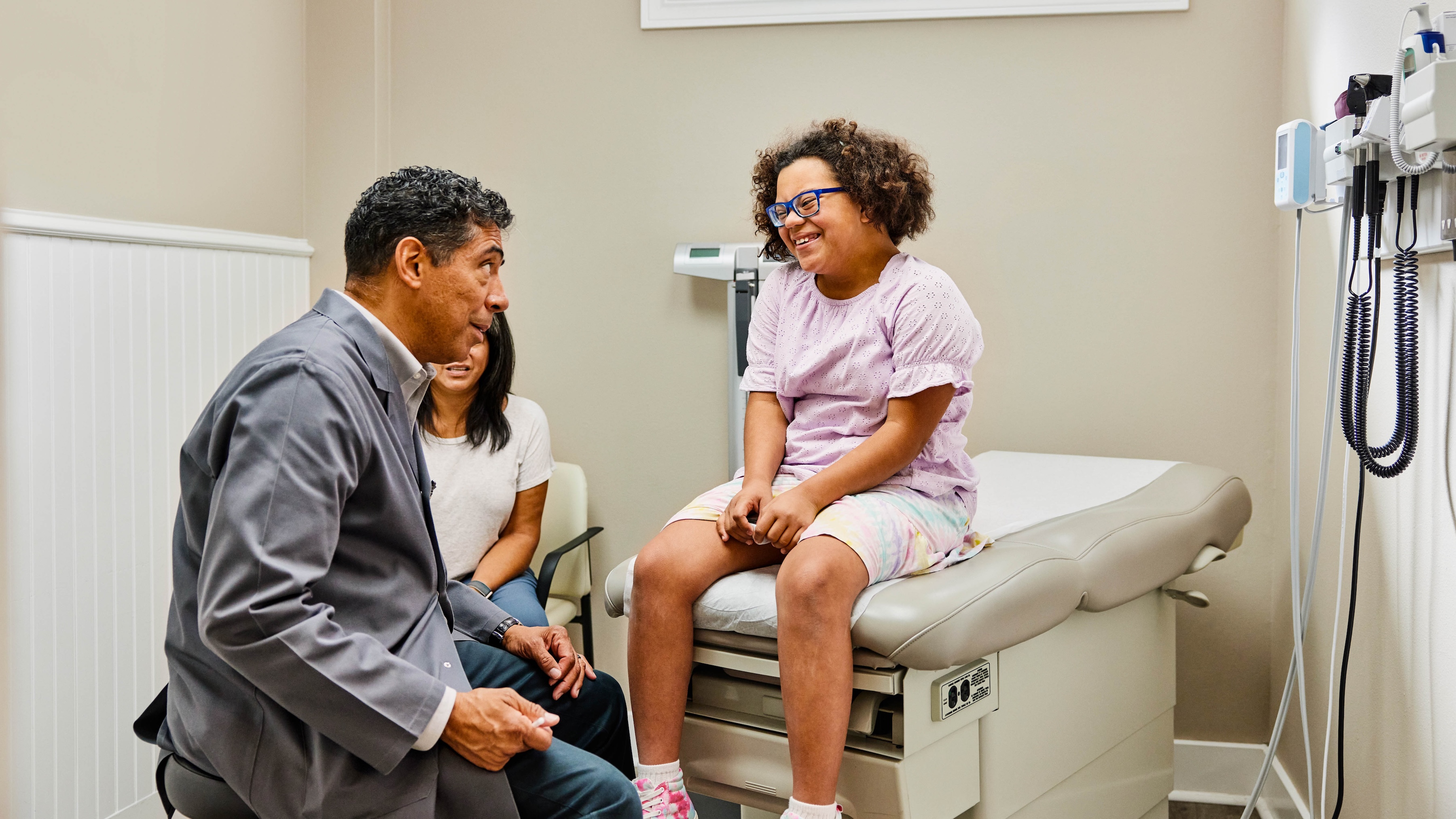 A pediatrician checking on a patient with a parent present.