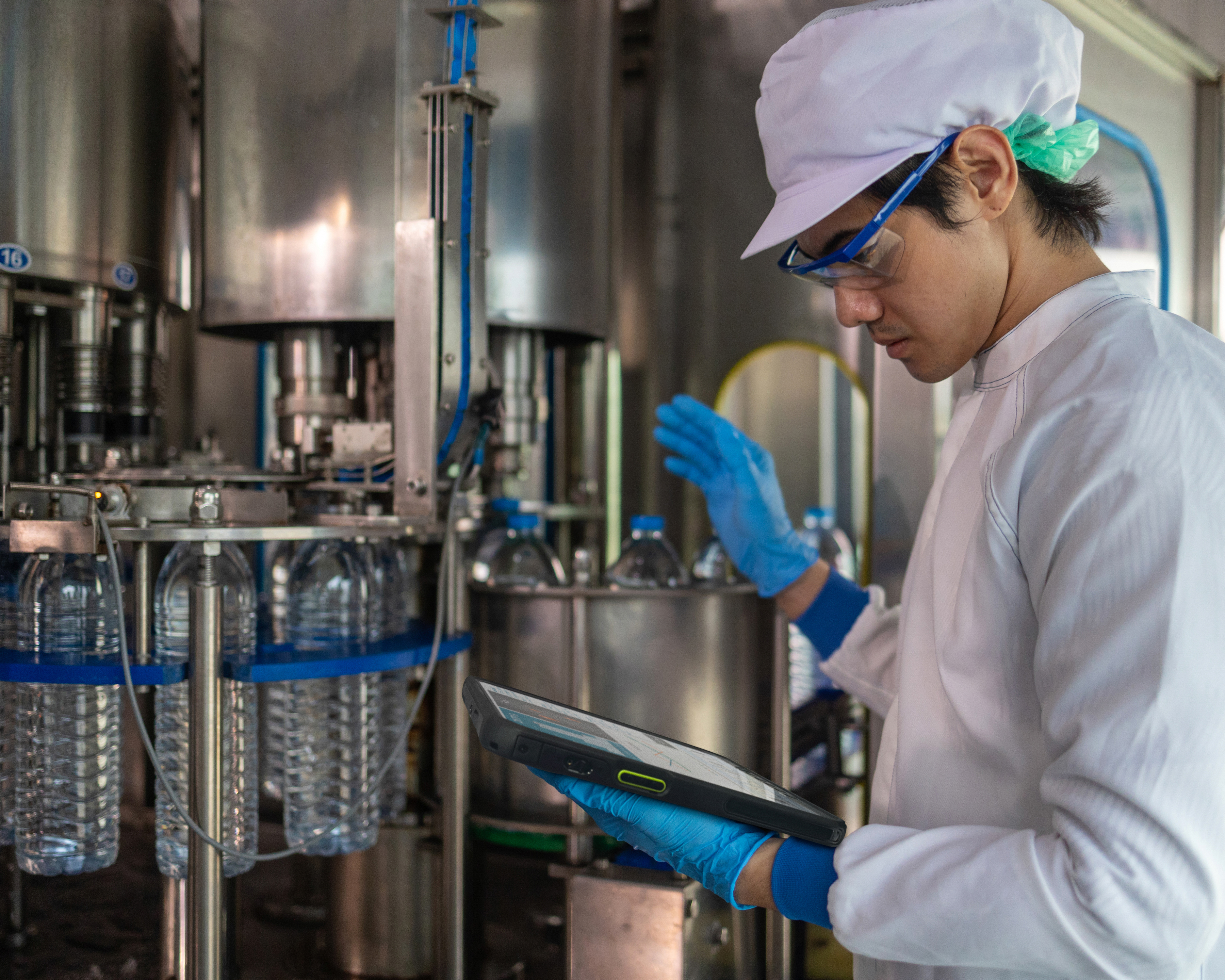 An engineer reviewing a tablet inside of a water bottle manufacturing facility.