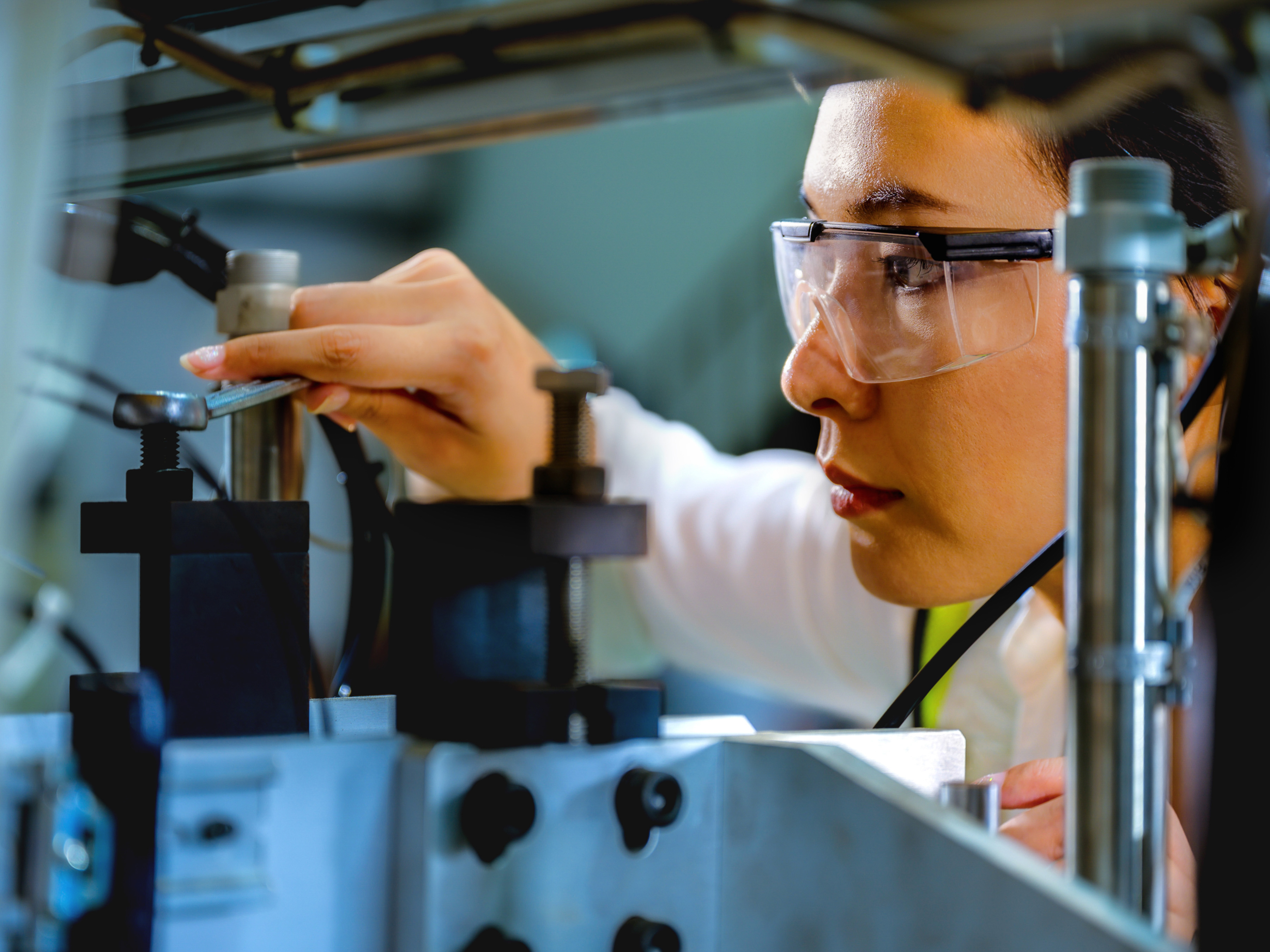 A technician uses a wrench to adjust a bolt on industrial machinery.