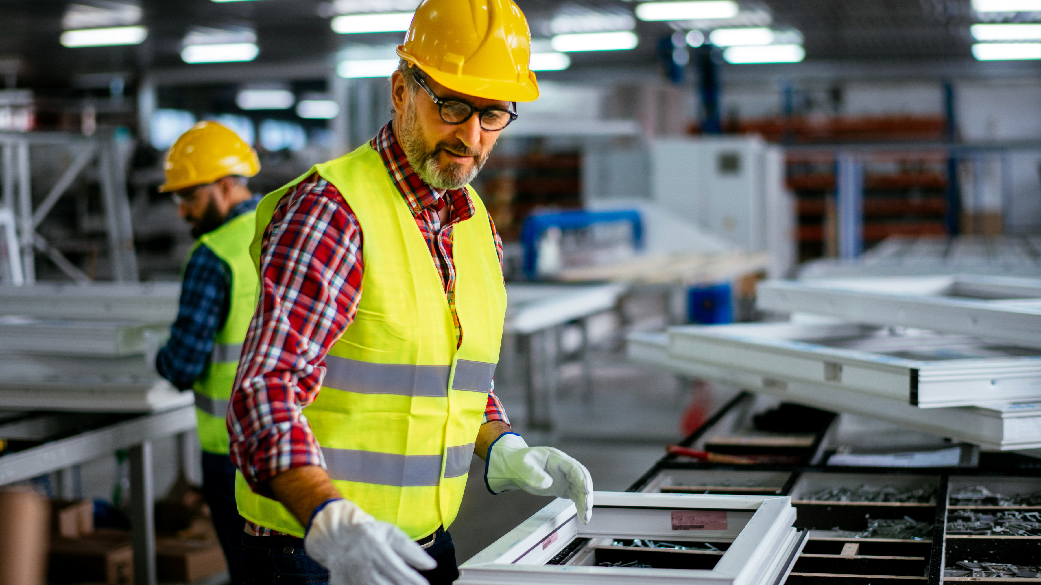 A worker assembling windows inside of a manufacturing plant.