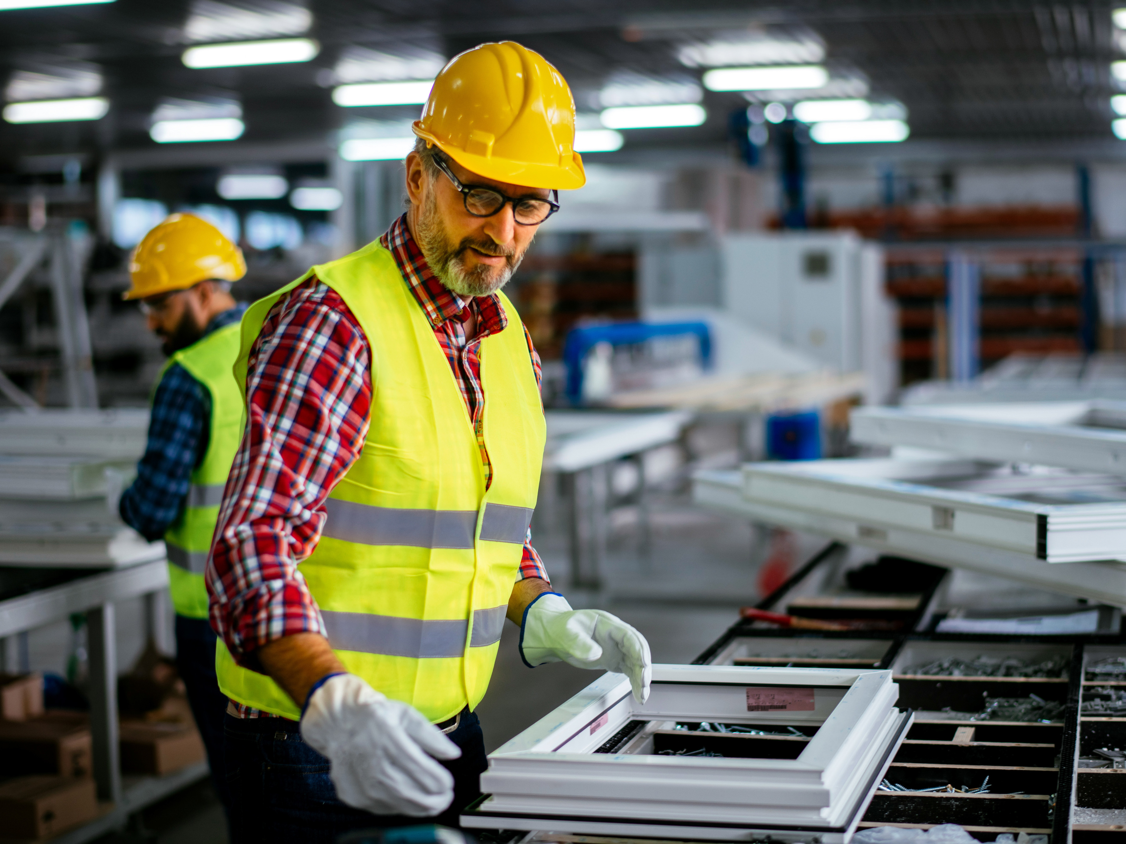 A worker assembling windows inside of a manufacturing plant.