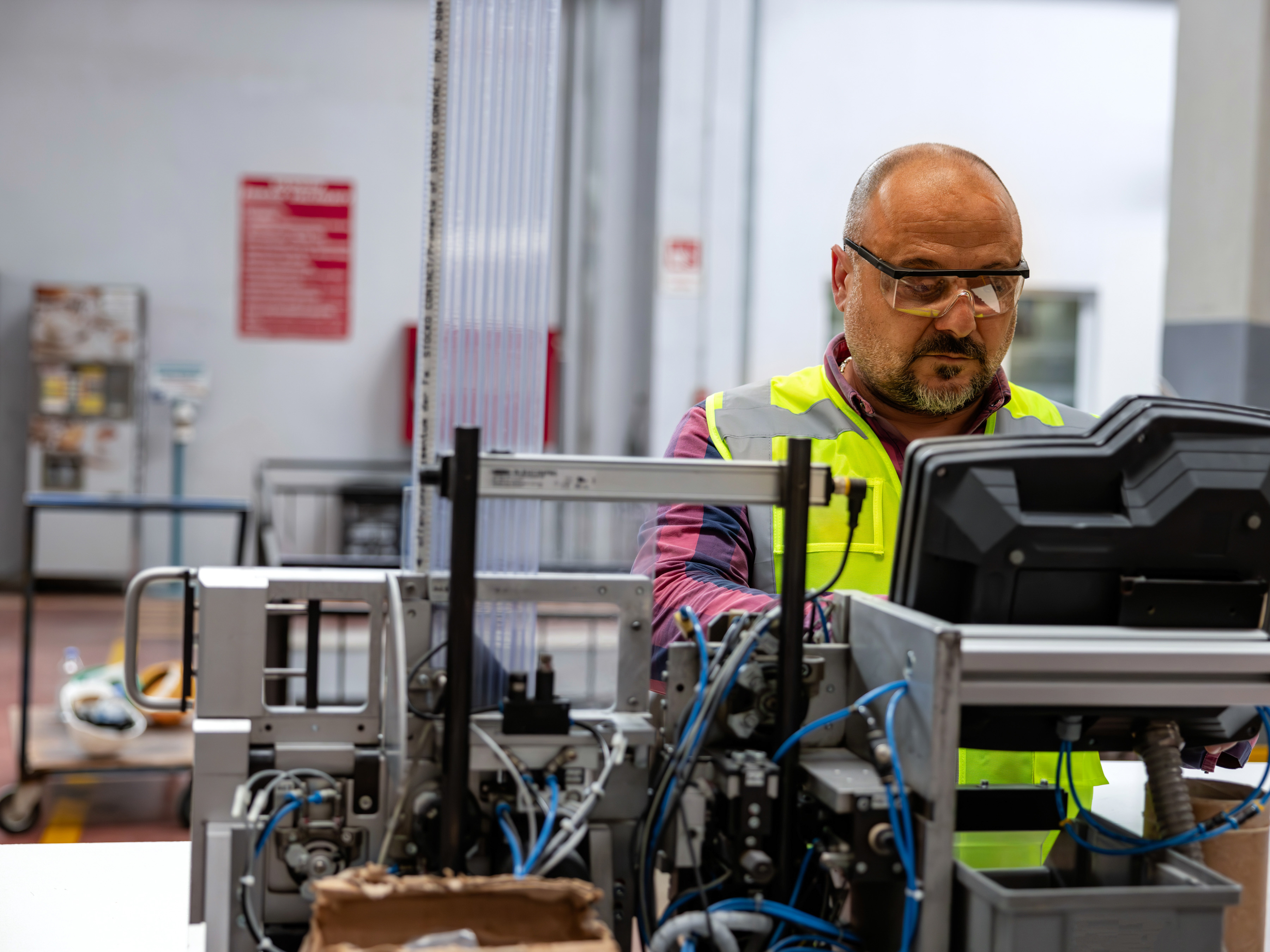 A worker looks at a screen while managing machinery in a factory.