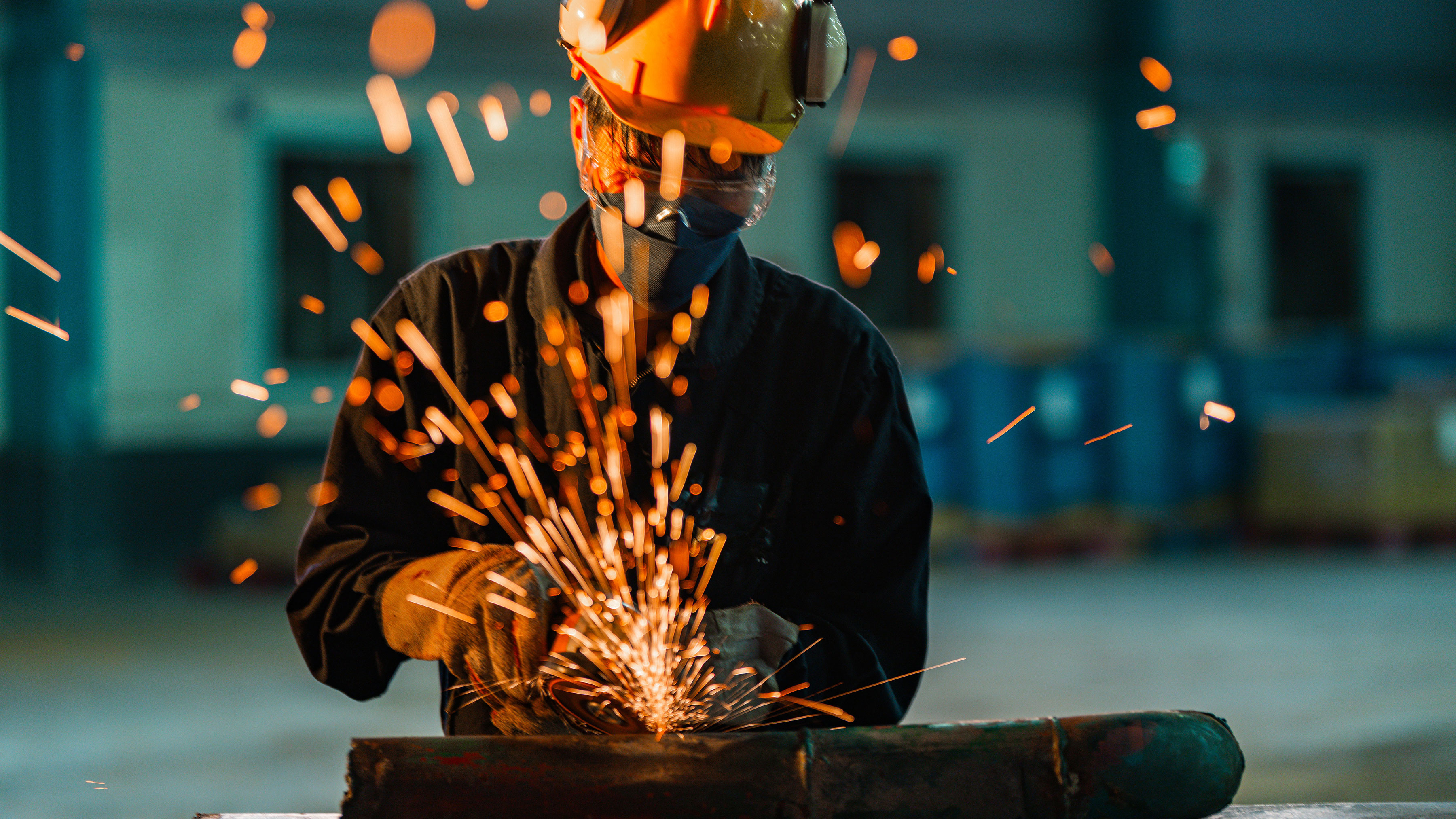 Steel worker grinding a pipe in a factory.