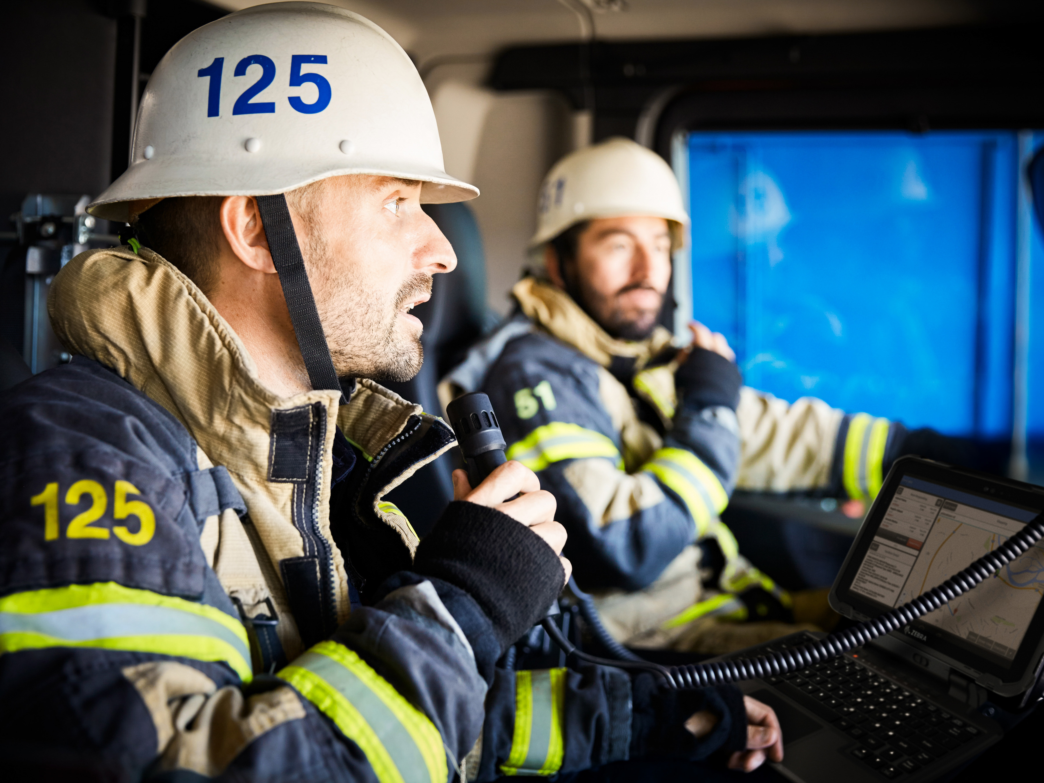 Two firefighters reviewing a Zebra ugged tablet inside of a firetruck.