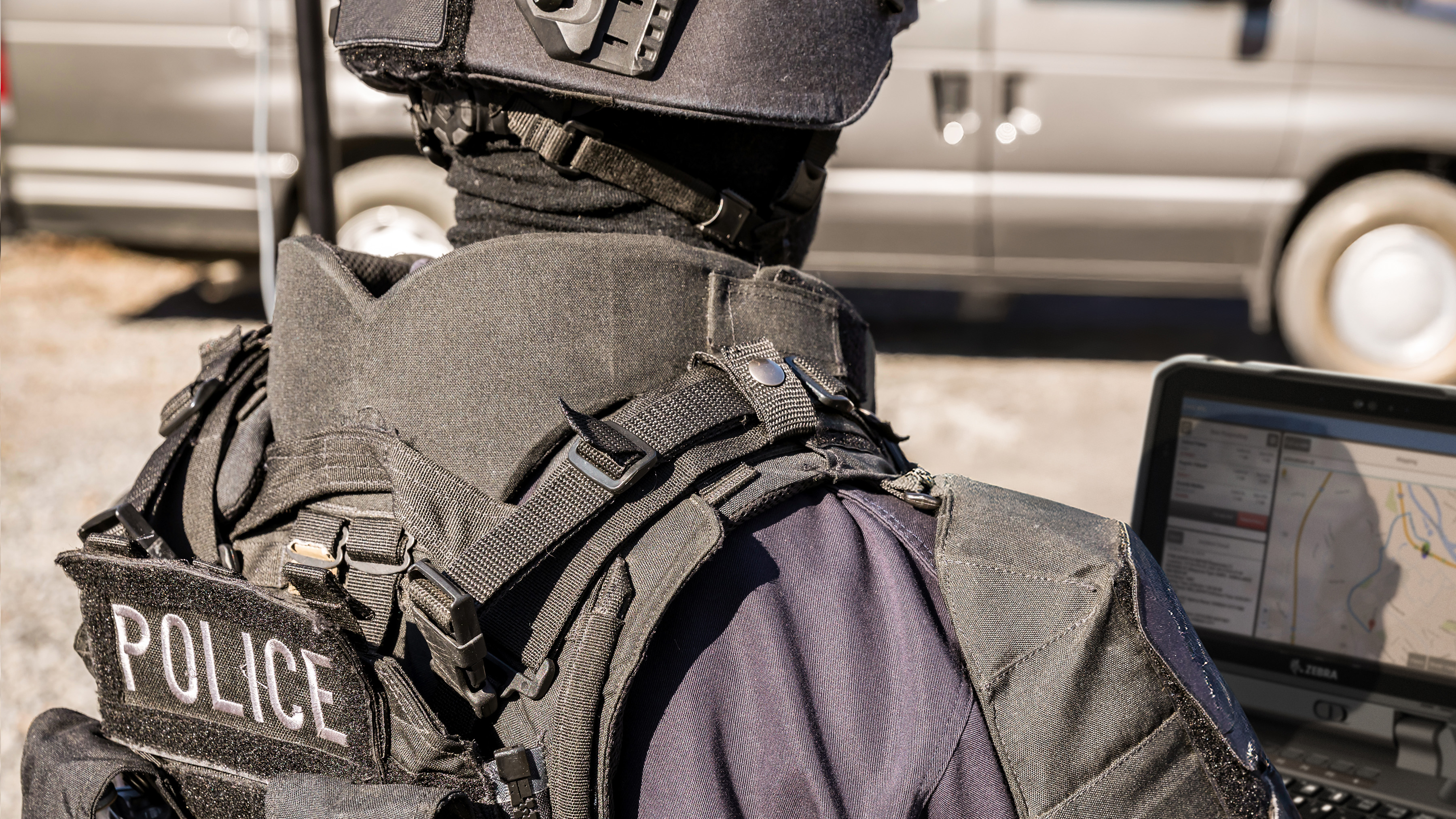 A tactical police officer using a Zebra rugged handheld tablet during a field operation.