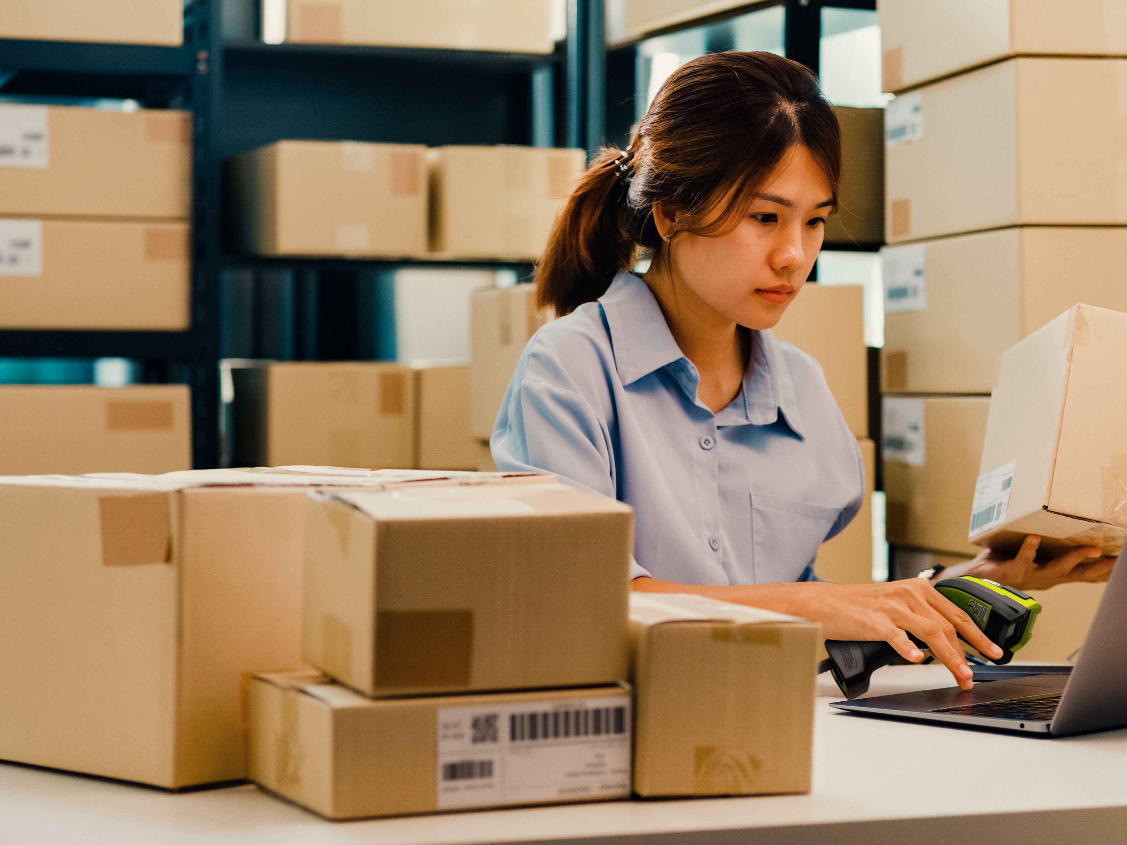 An employee handling box deliveries using a Zebra handheld barcode scanner.