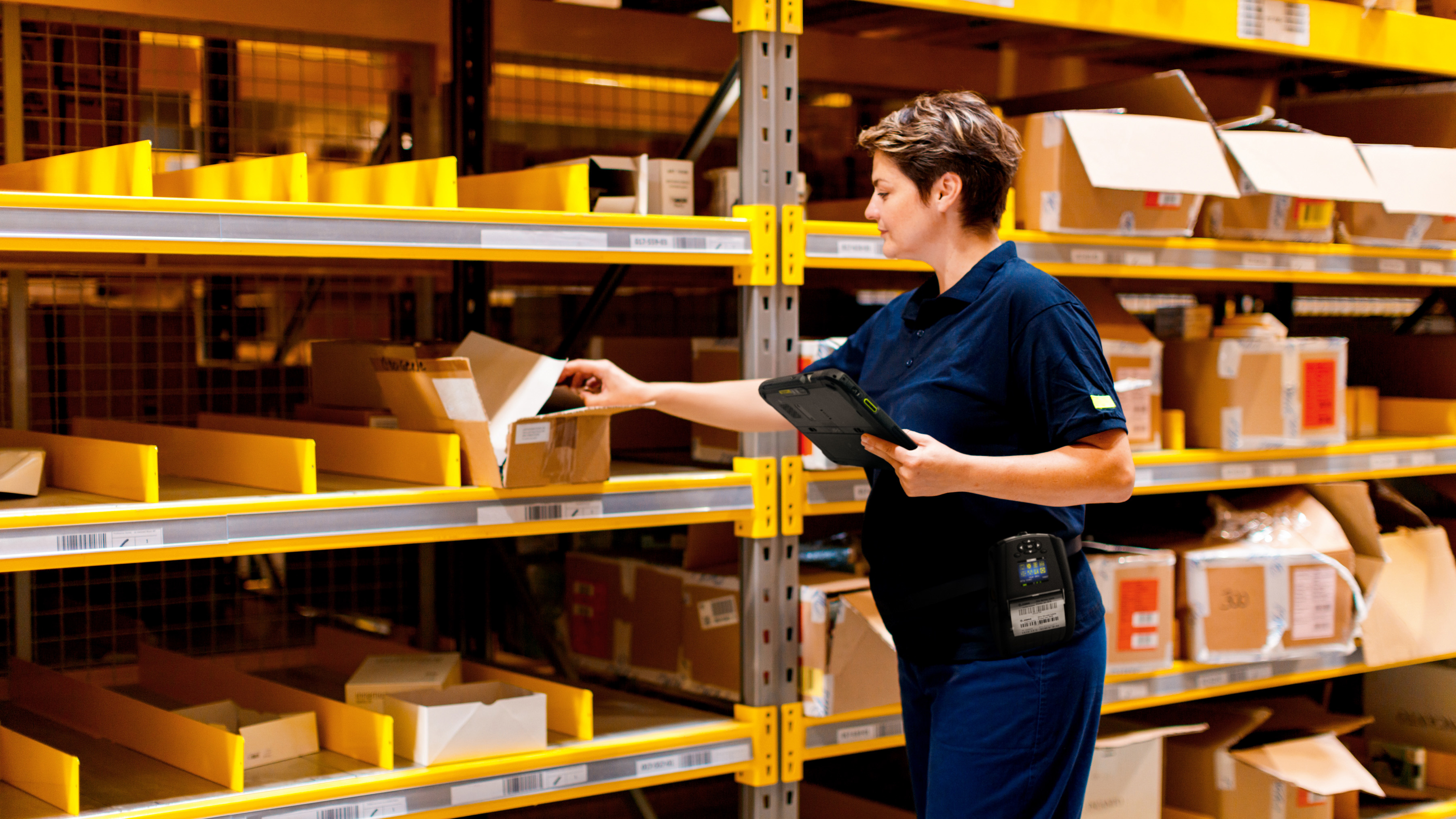 A retail worker with a Zebra tablet and mobile printer finding inventory in the store's back-of-house .