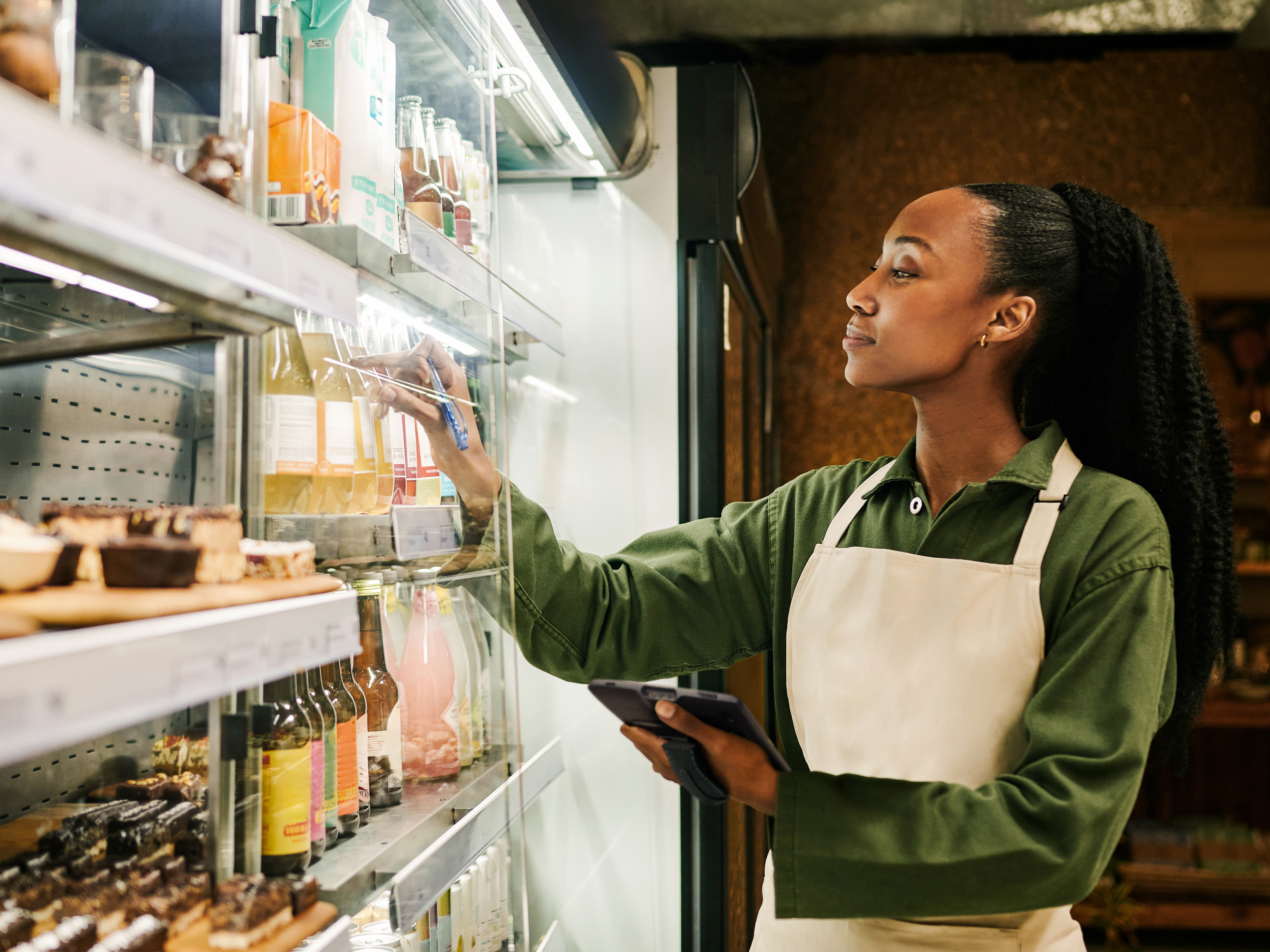 A front-of-house employee checking juice stock inside of a grocery store.