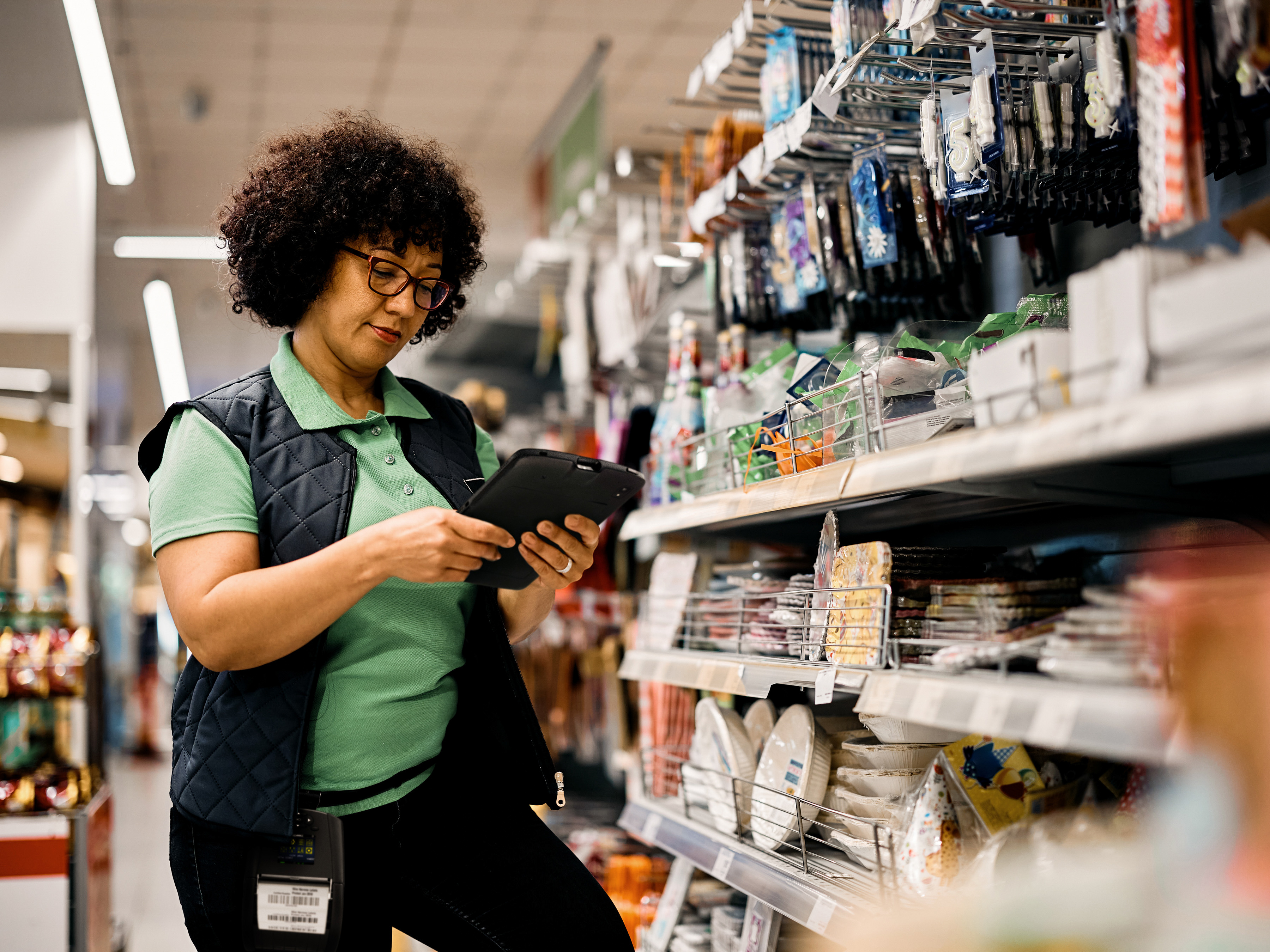 A front-of-house employee reviewing a tablet inside an aisle in a retail store.