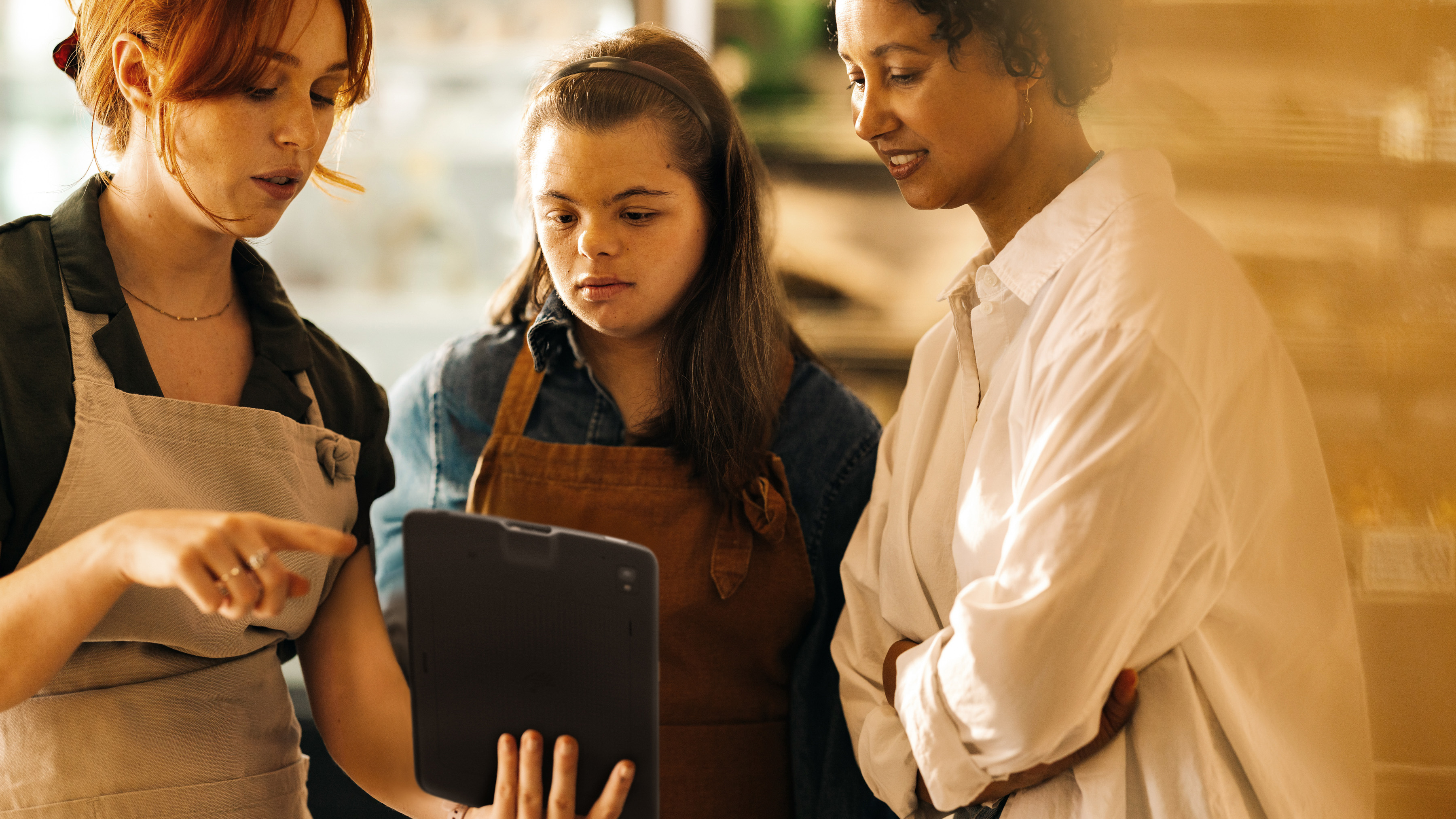 Two retail employees reviewing a tablet with a shopper inside a store's front-of-house.