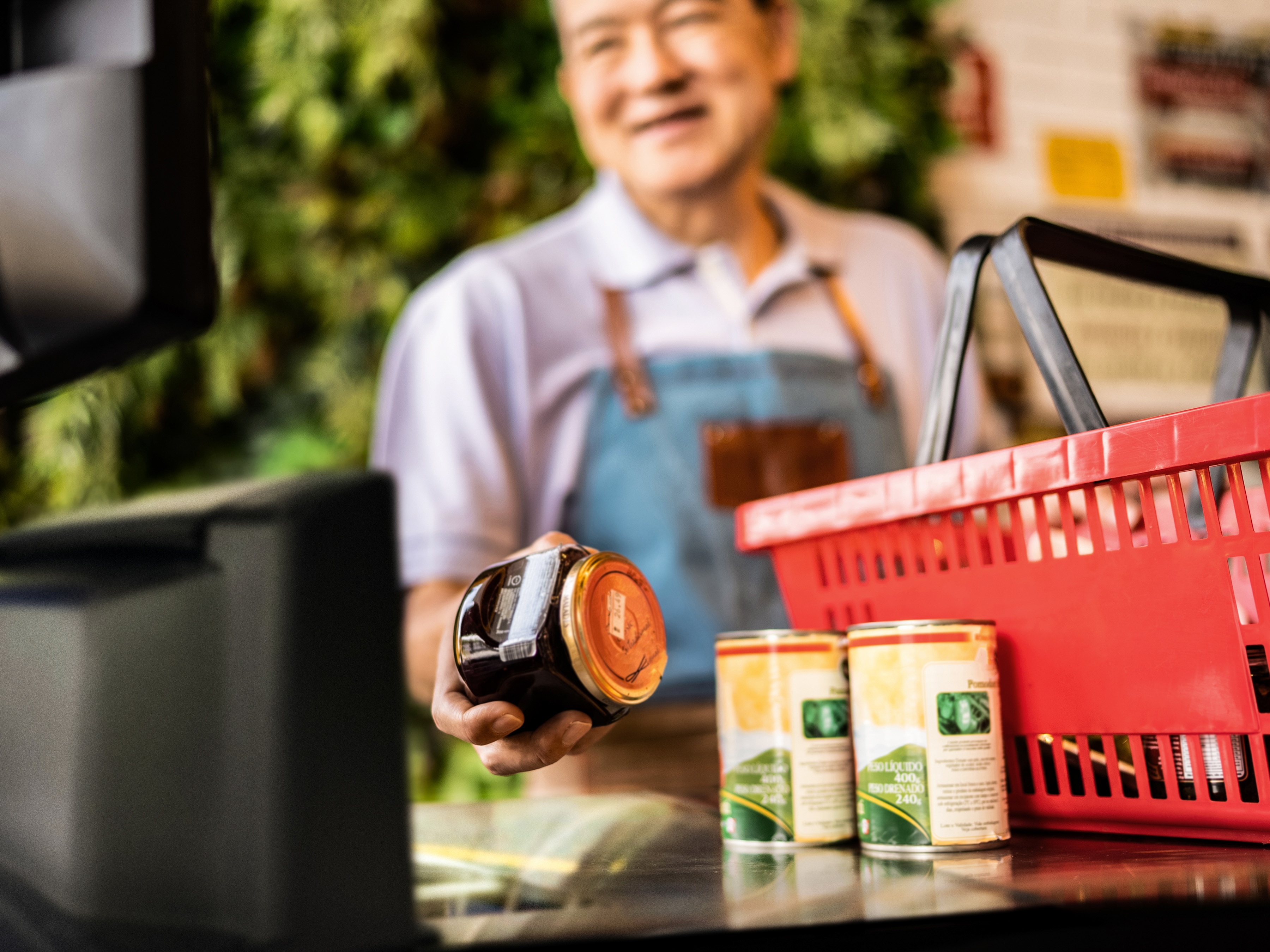 A front-of-house employee scanning a jar with a fixed mount scanner at a grocery store checkout.