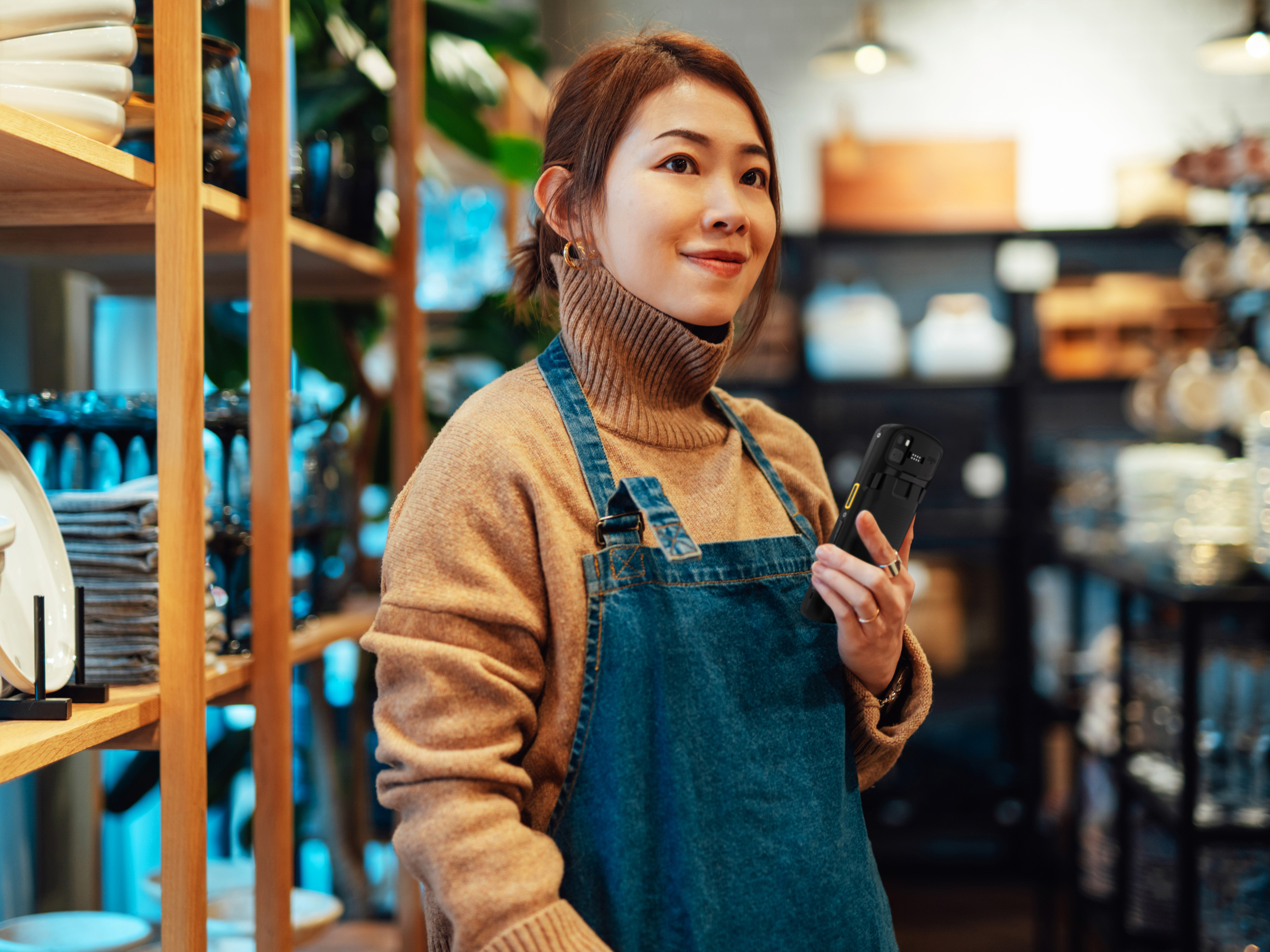 Front of house retail employee using a Zebra handheld mobile computer in a homeware store.