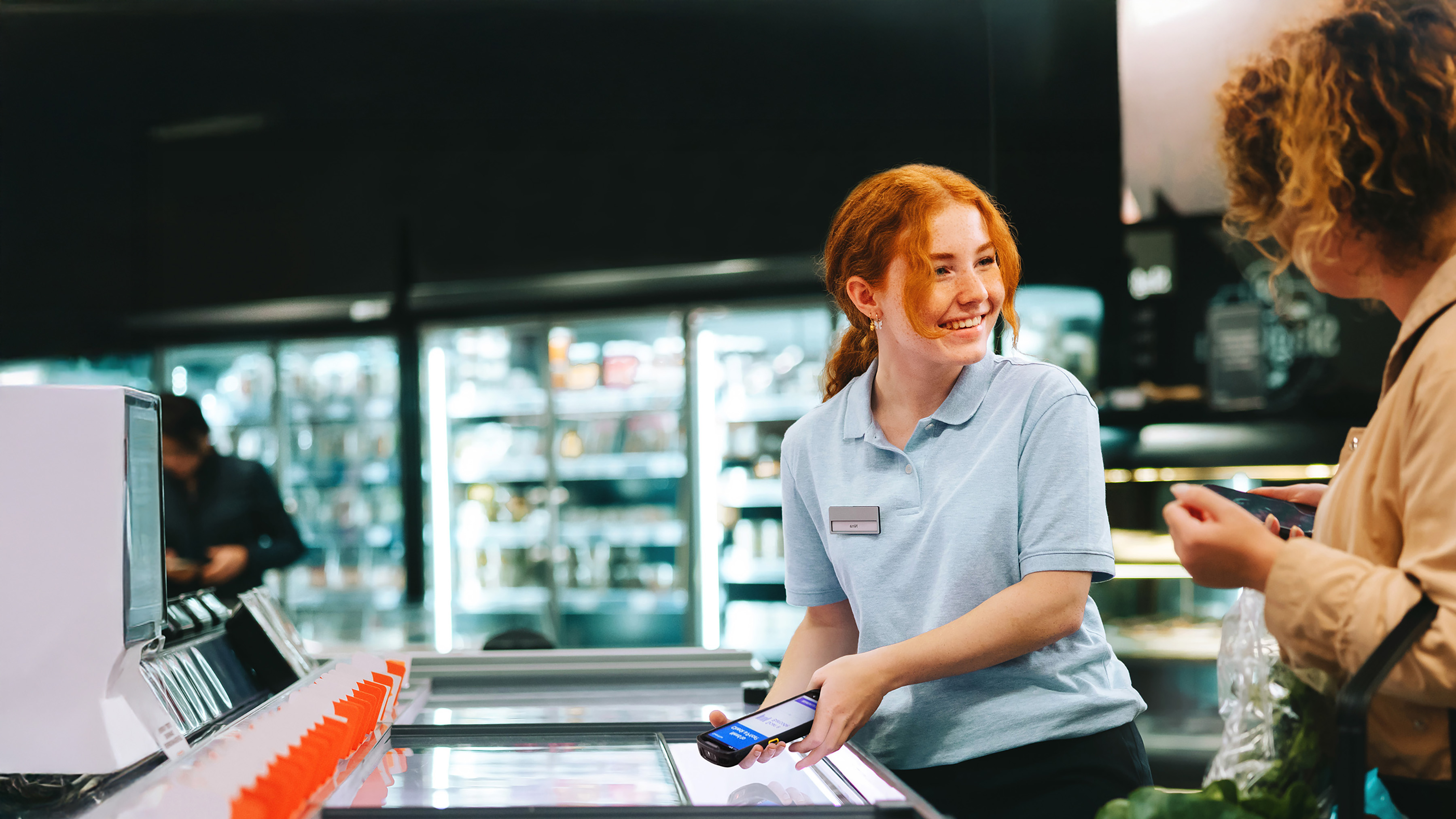 Grocery store employee assisting customer using a handheld mobile computer.