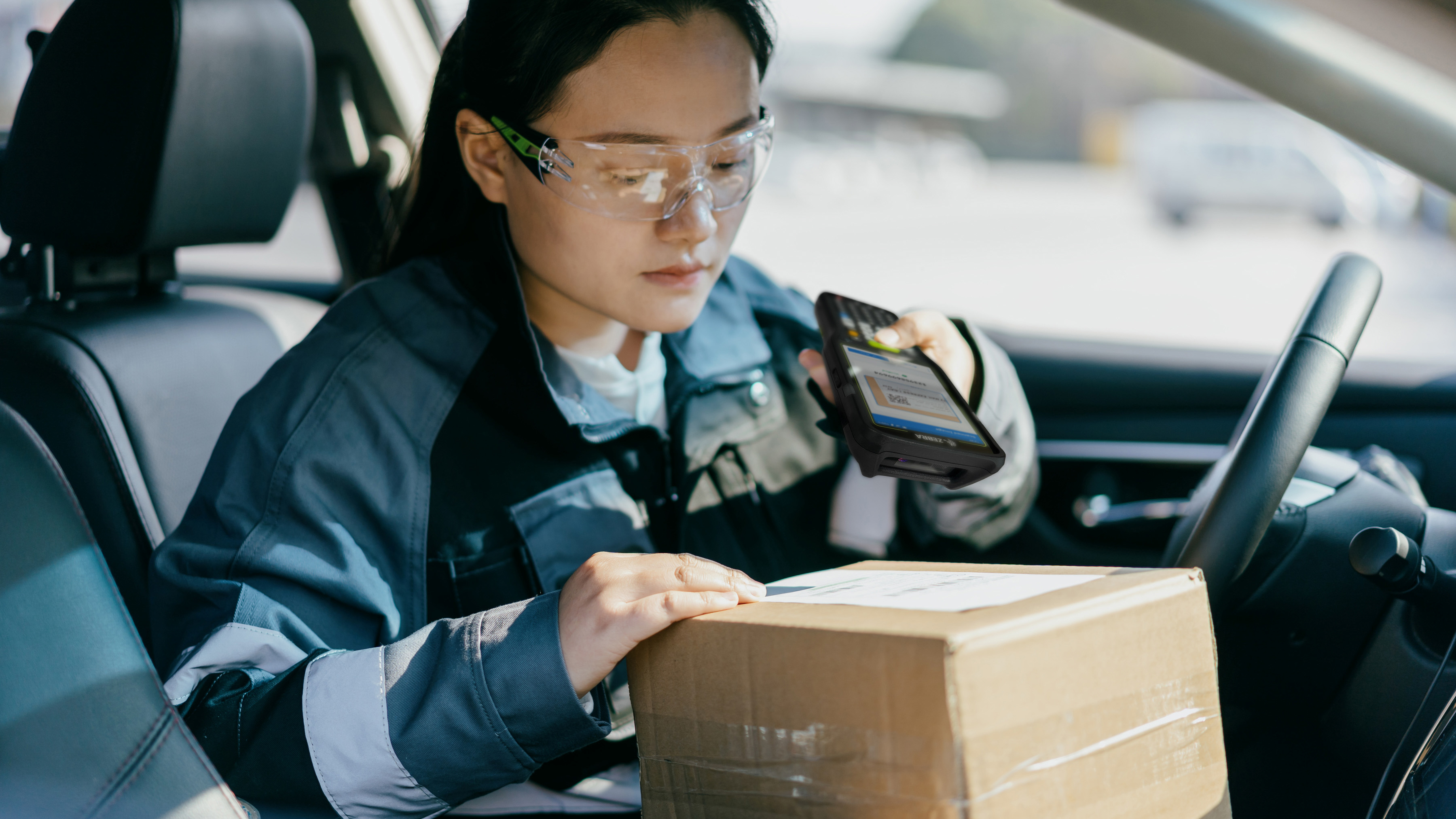 Courier in a delivery vehicle scanning a parcel with a Zebra handheld mobile computer.