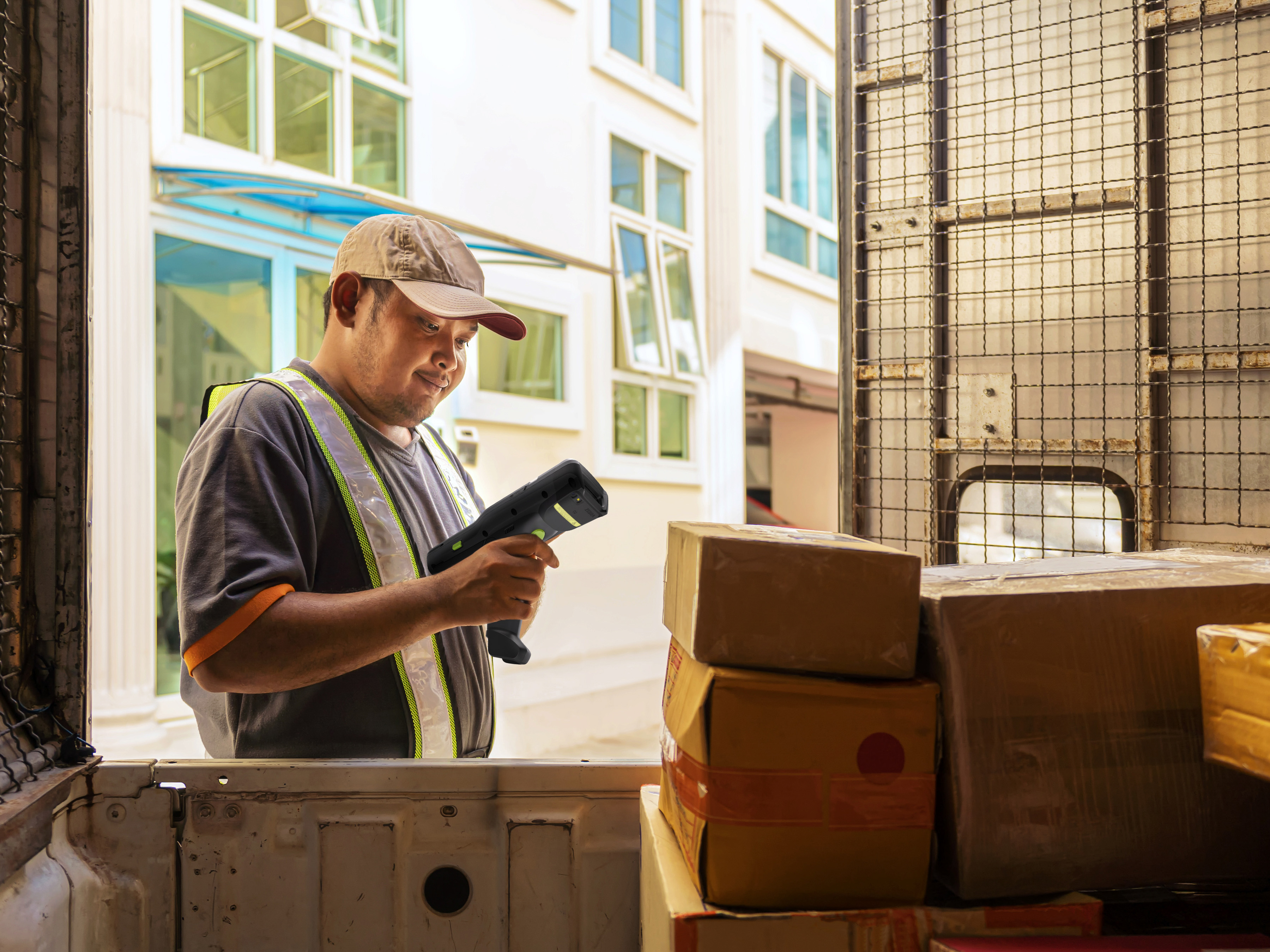 Courier using a Zebra handheld mobile computer to scan a parcel in the back of a delivery truck.