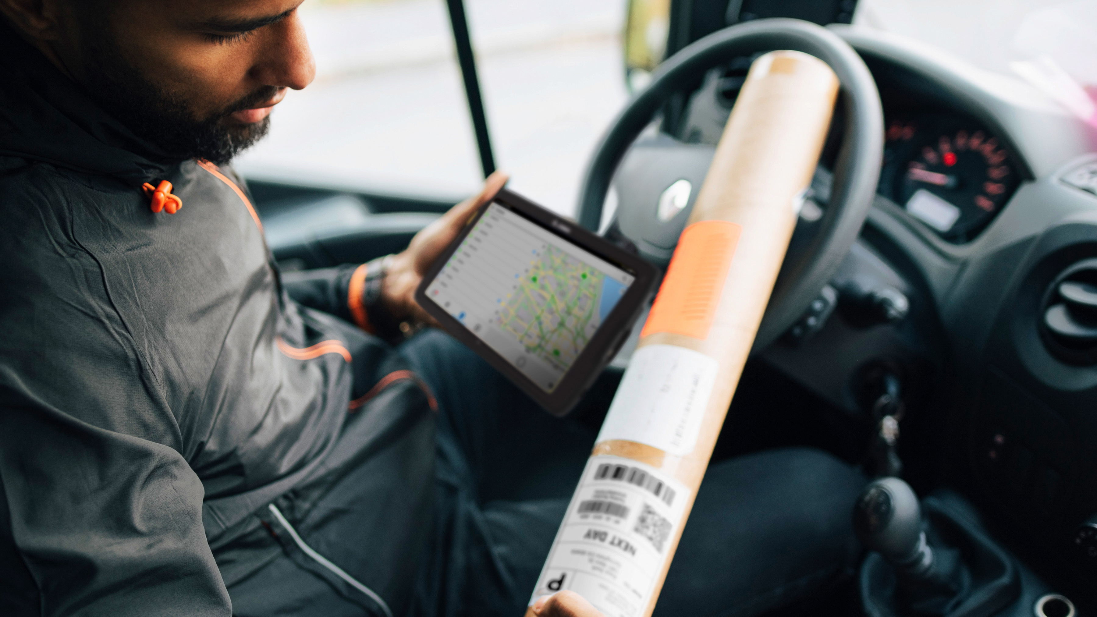 Courier in a delivery vehicle using a Zebra tablet.