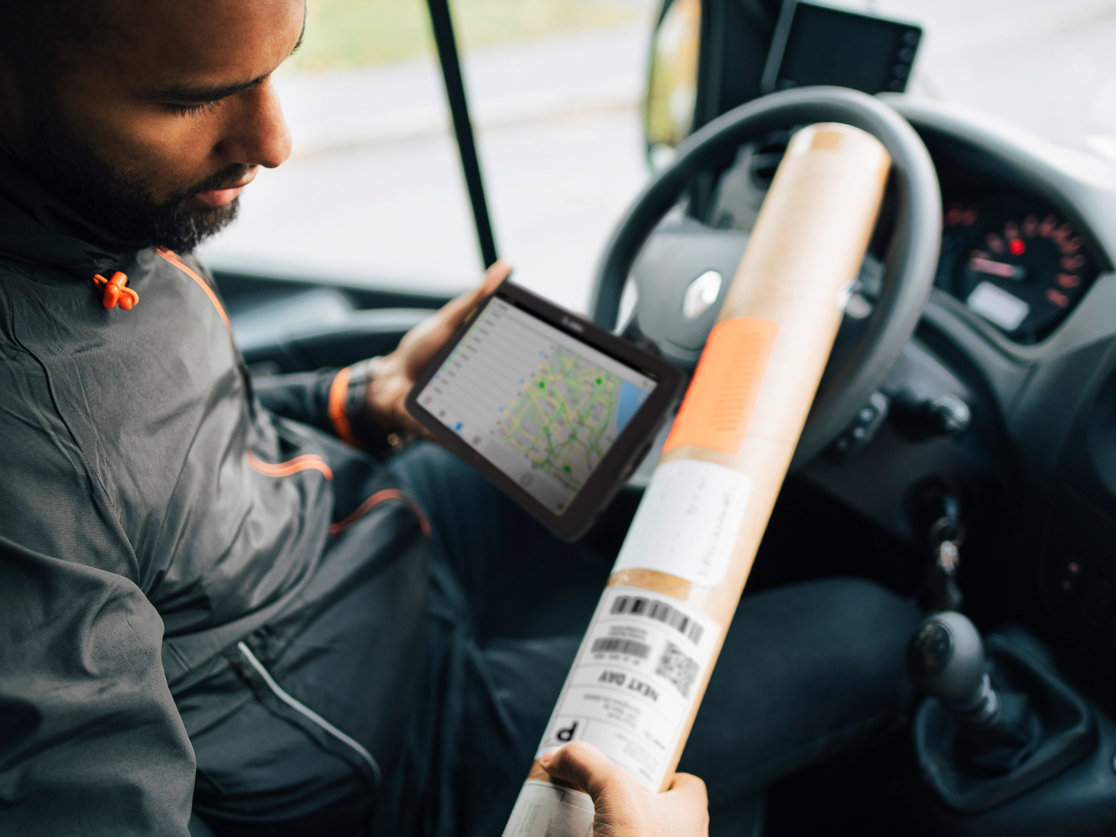 Courier in a delivery vehicle using a Zebra tablet.