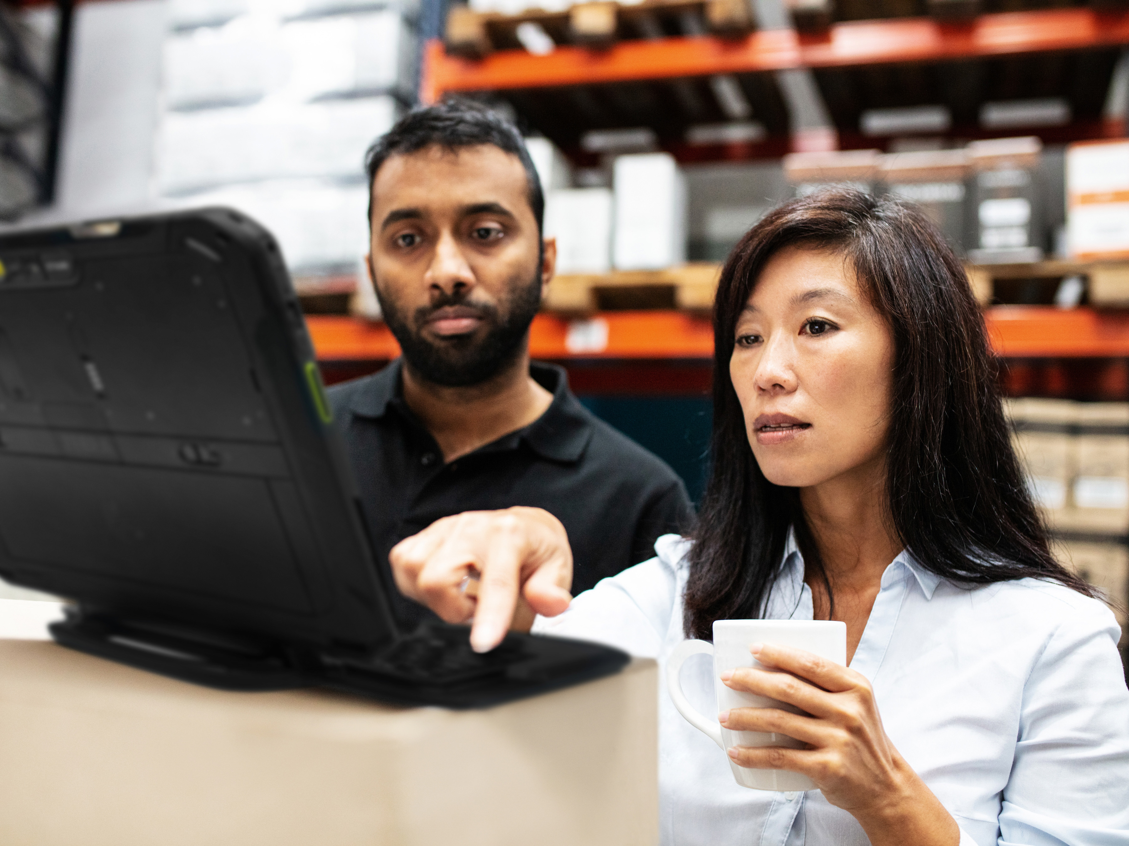 Employees reviewing a Zebra tablet in a warehouse.