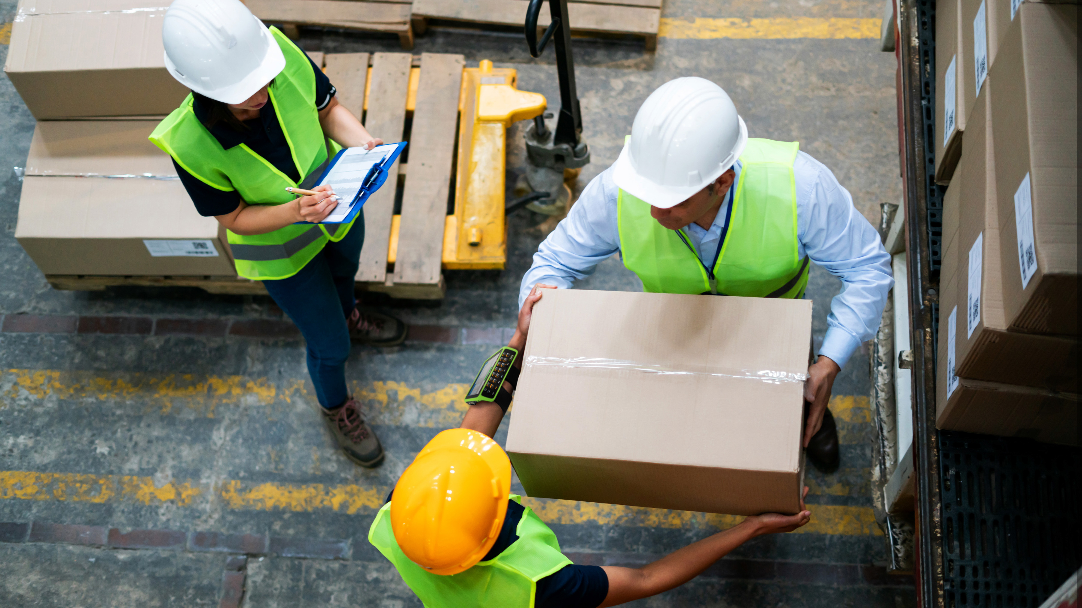 Workers with Zebra mobile computer unloading a forklift in a warehouse