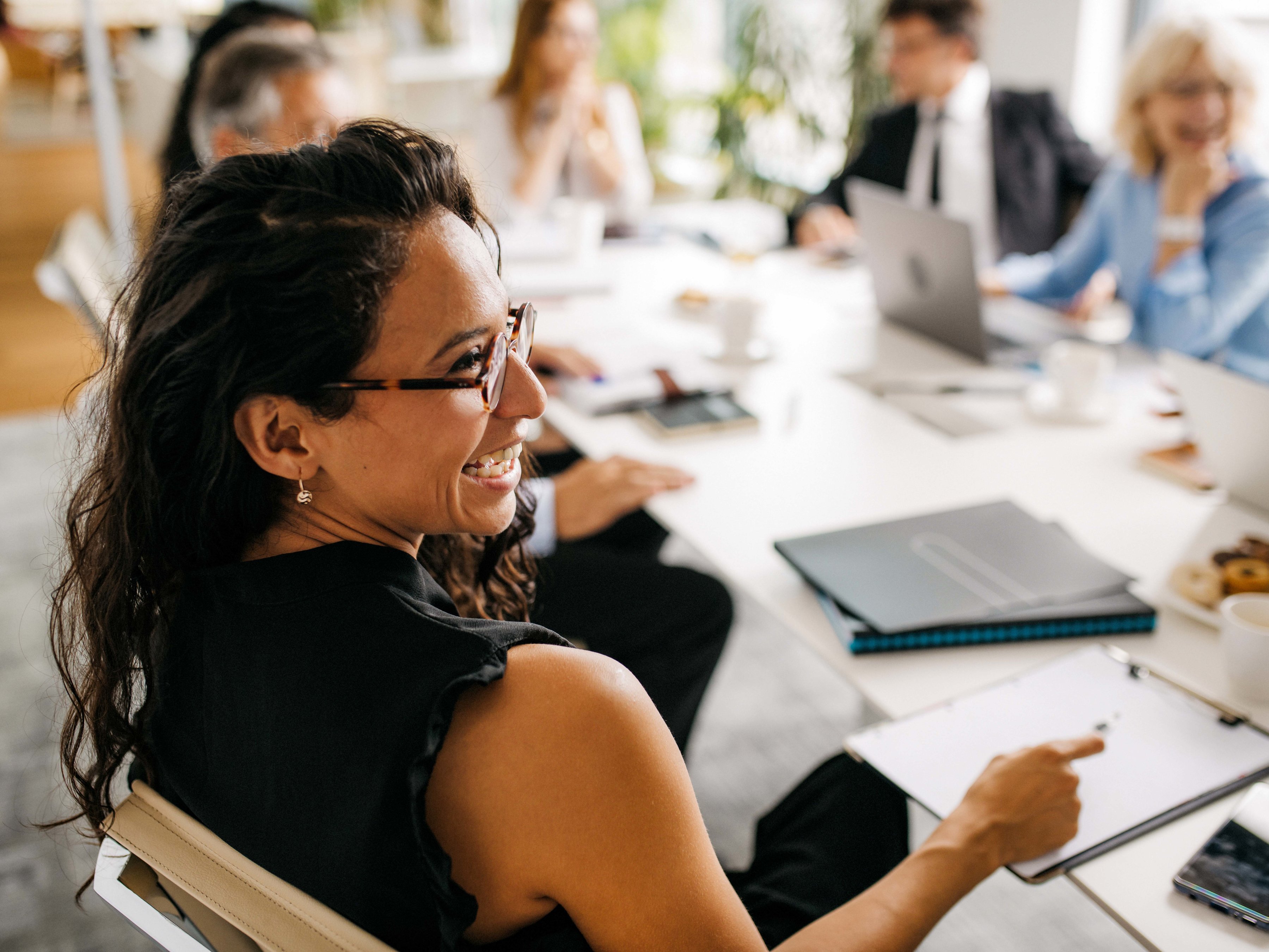 An employee with a group of colleagues are seated around a conference table engaged in a meeting.