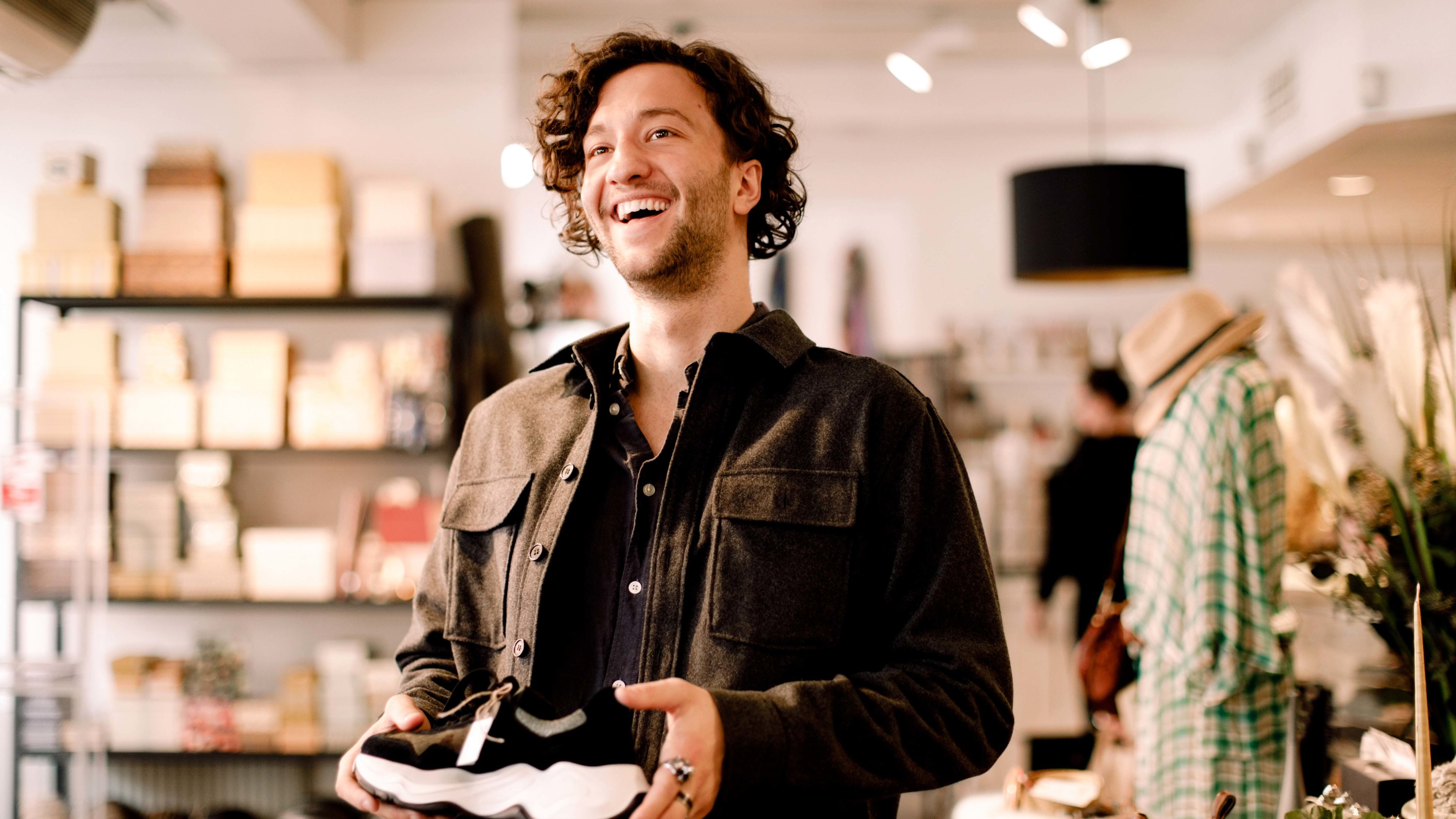 A customer is holding a sneaker and shopping in a retail store.