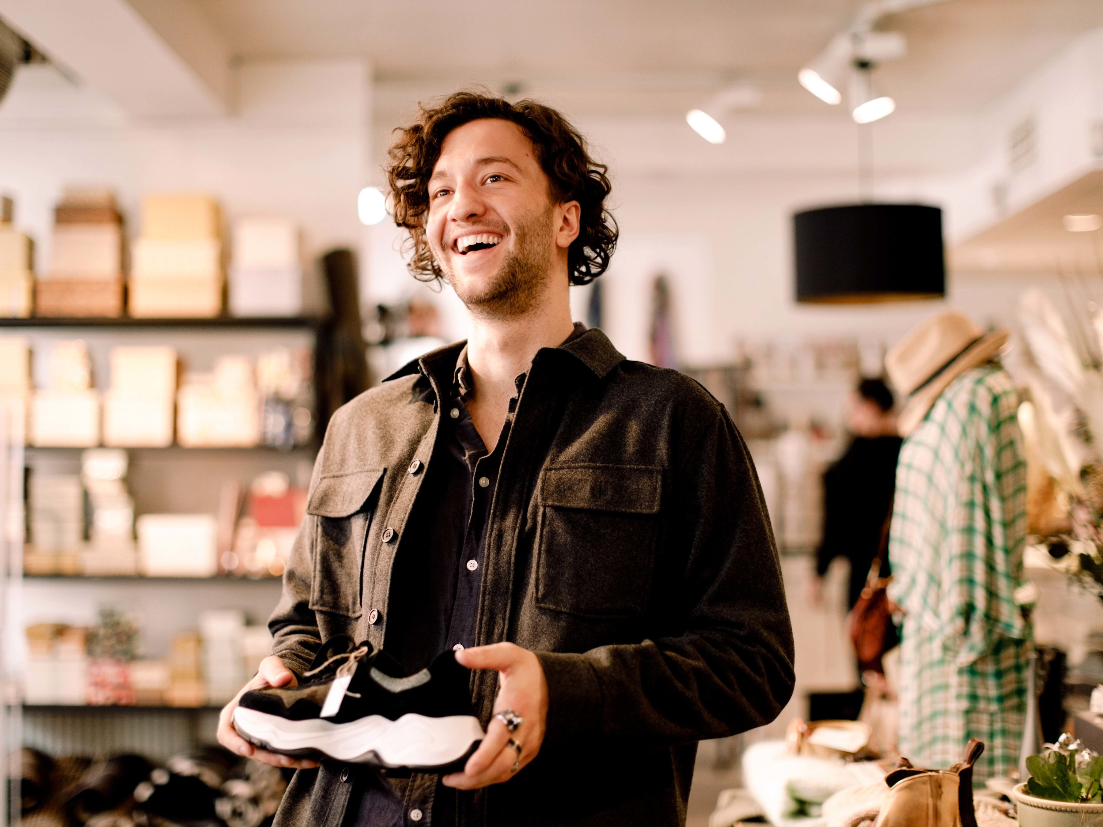 A customer is holding a sneaker and shopping in a retail store.