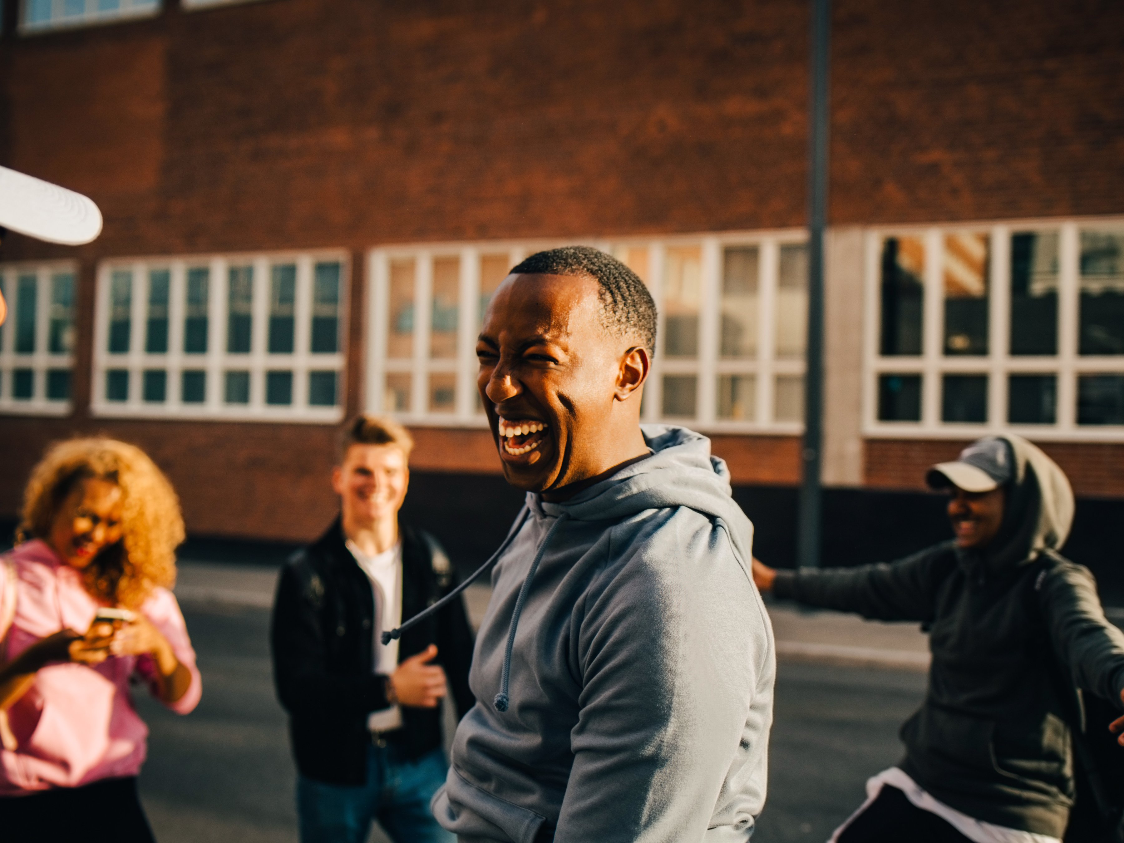 A group of friends smiling and laughing together in an outdoor setting.