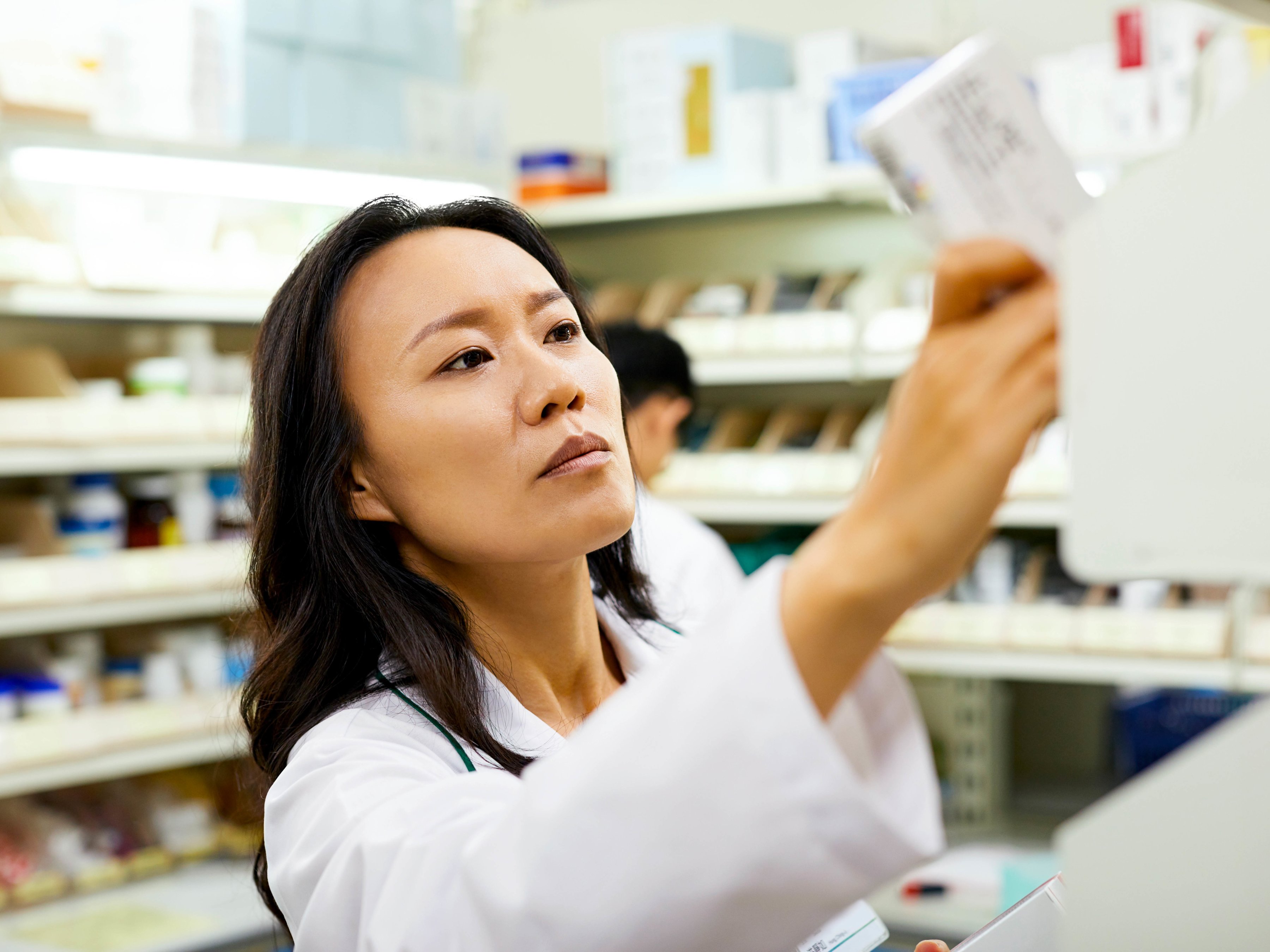A pharmacist taking out a box of medicine from the shelf.