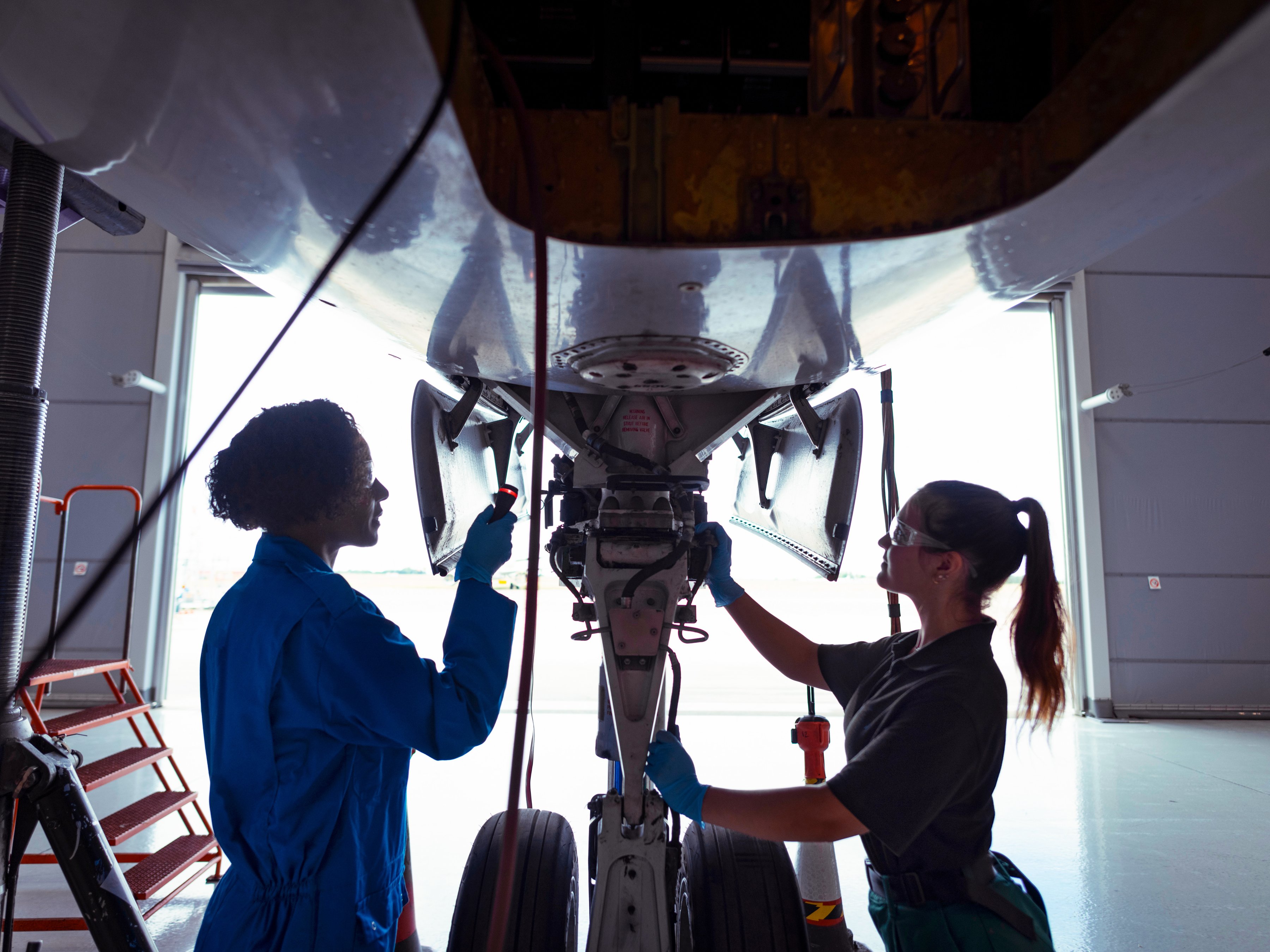 Aircraft engineers inspecting the landing gear on a jet. 