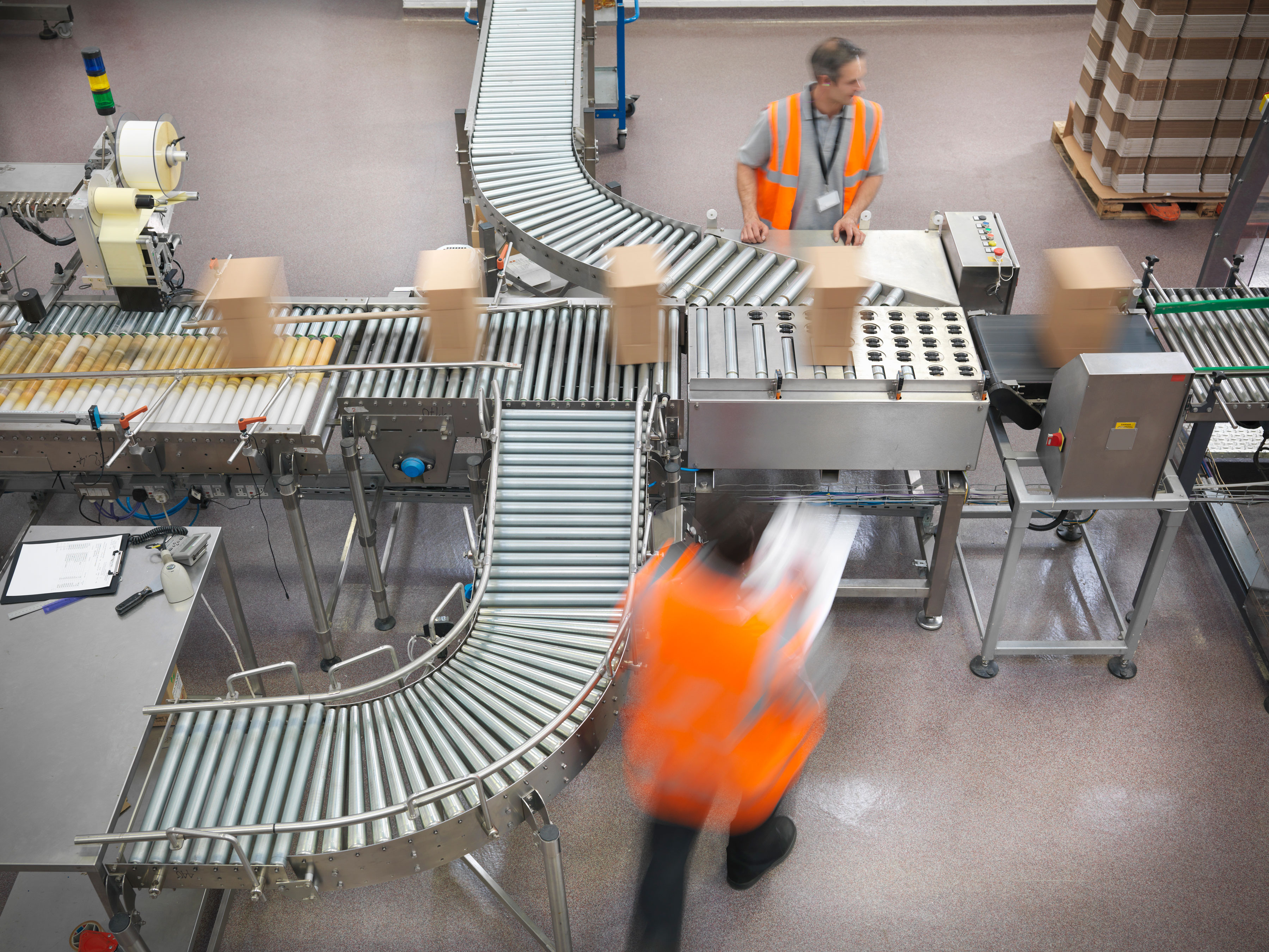 Two manufacturing employees overseeing the factory conveyor belt with Zebra fixed industrial scanner. 