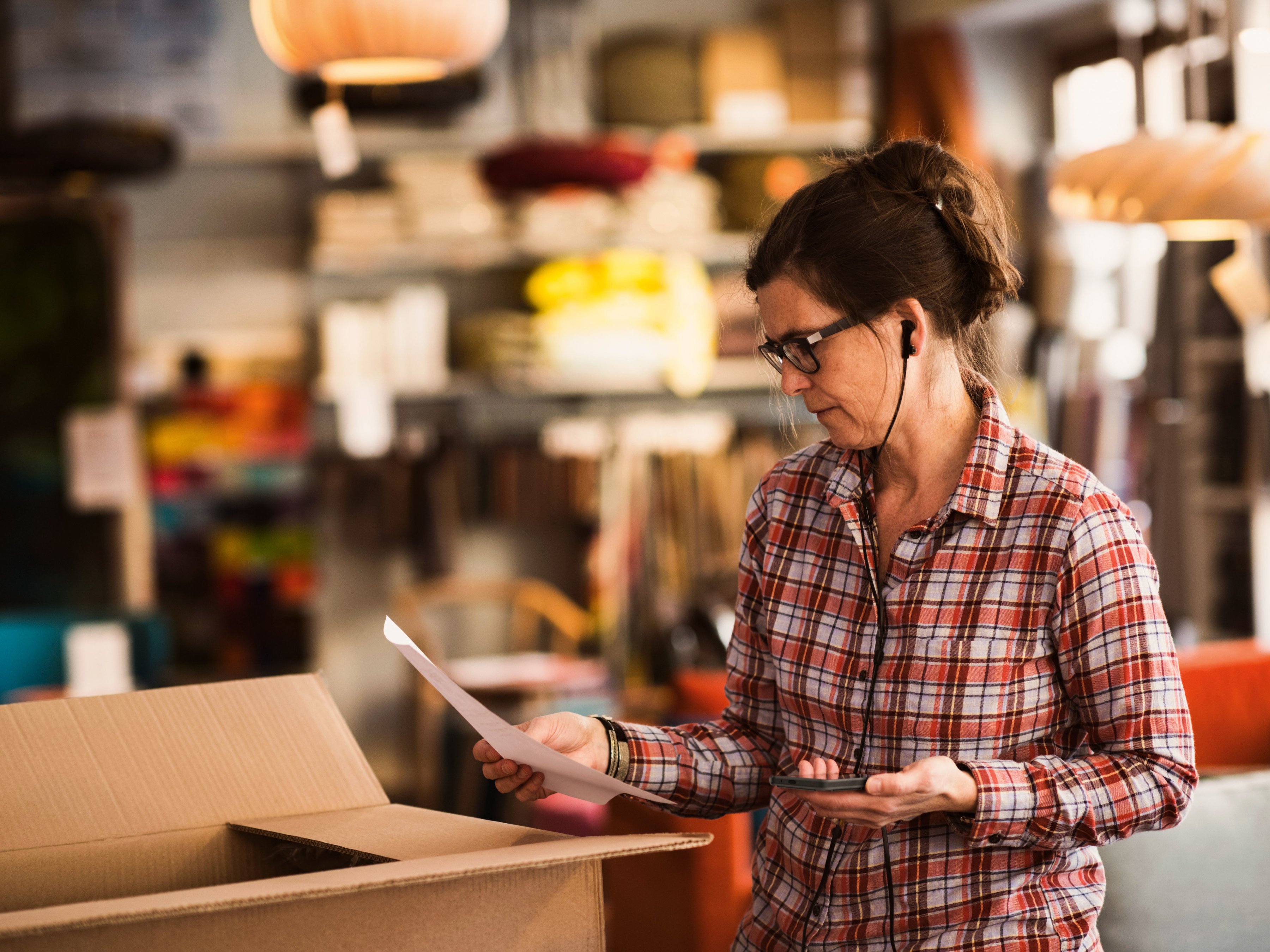 A back-of-house employee is receiving delivery and reviewing paperwork while using a handheld mobile computer.