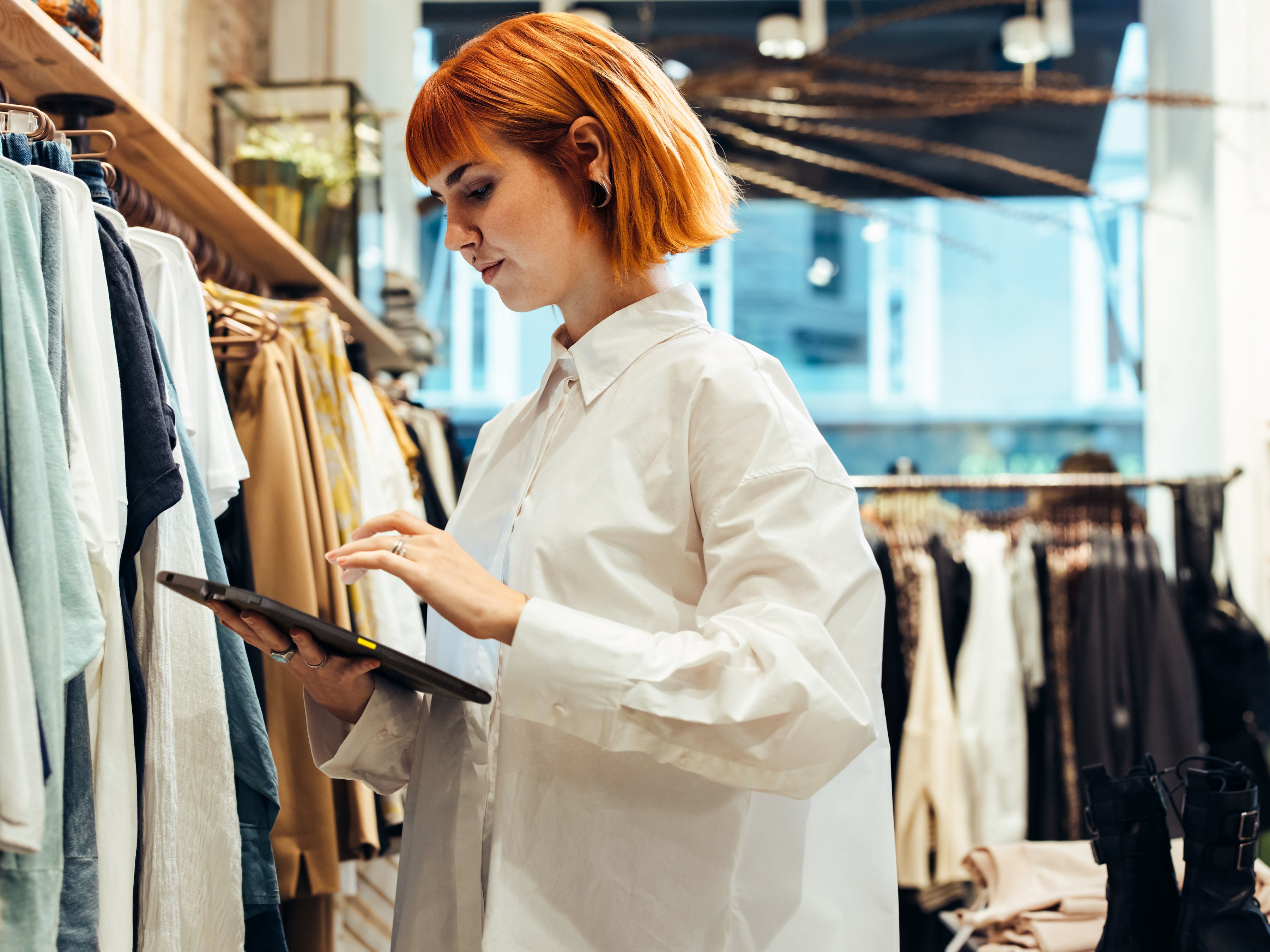 A retail employee reviewing a tablet inside of a clothing store.