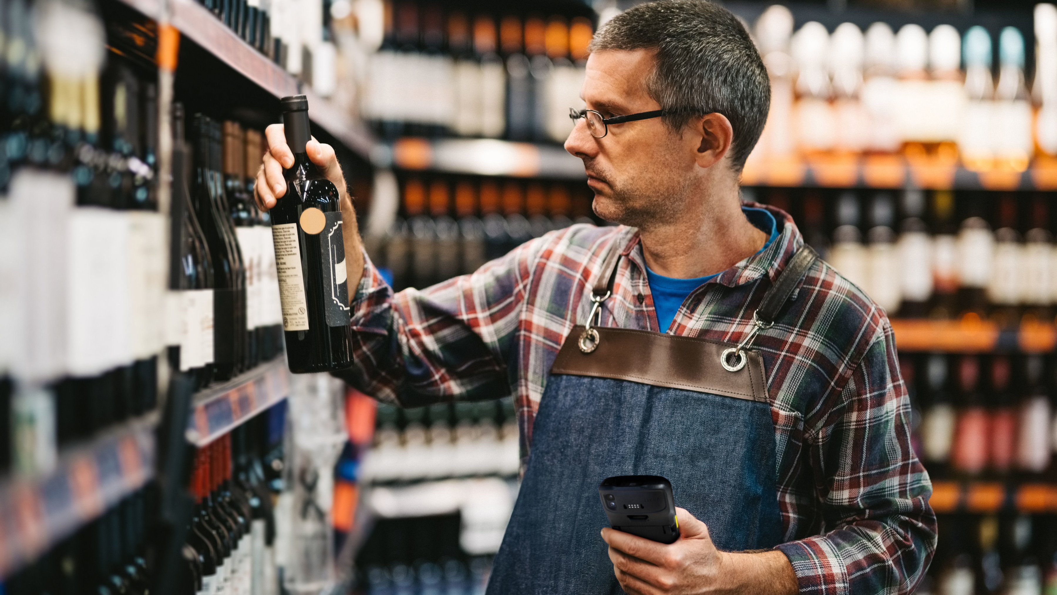 A front-of-house employee using a tablet to check inventory inside of a wine store.