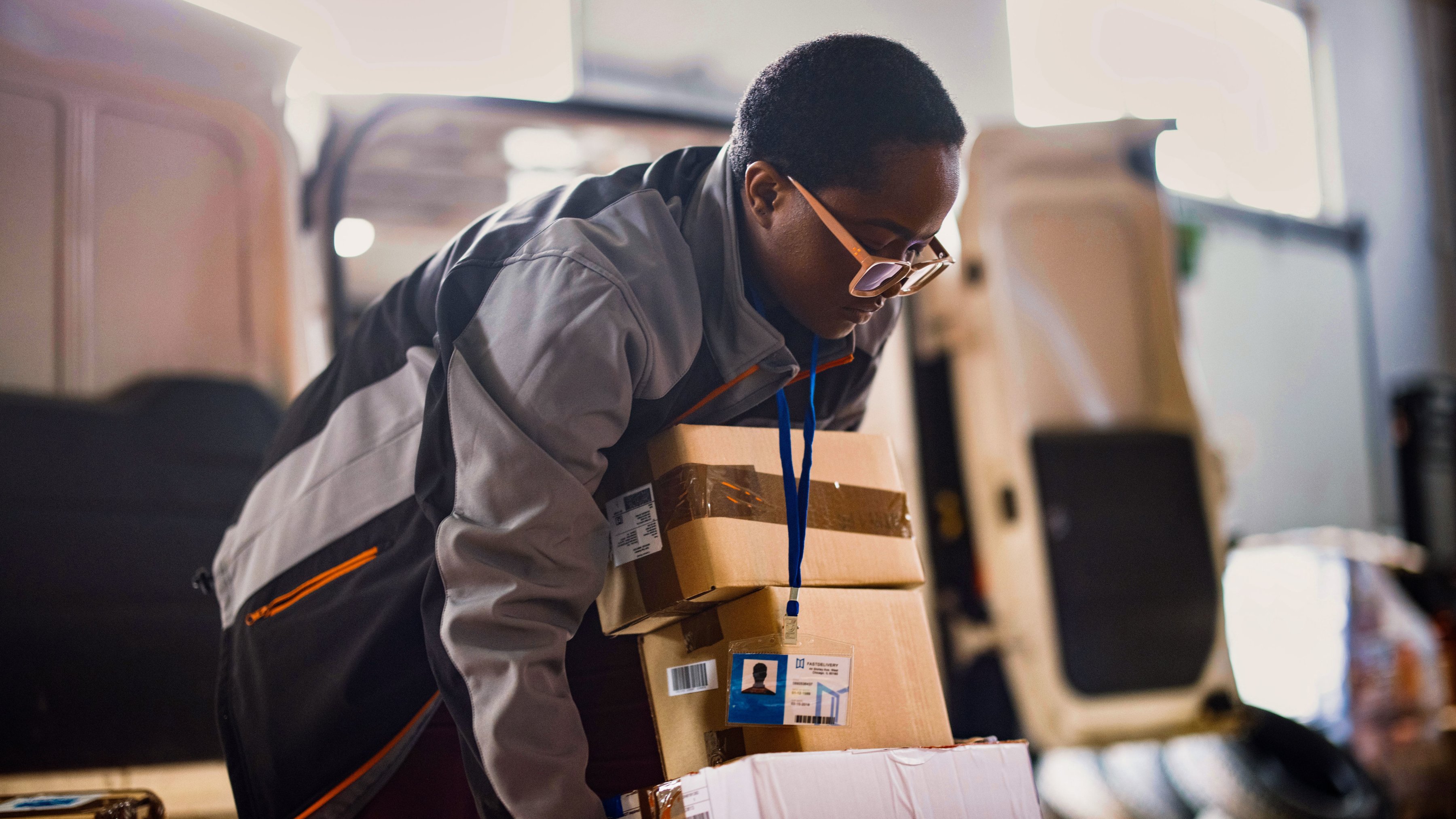 Postal worker carrying delivery boxes. 