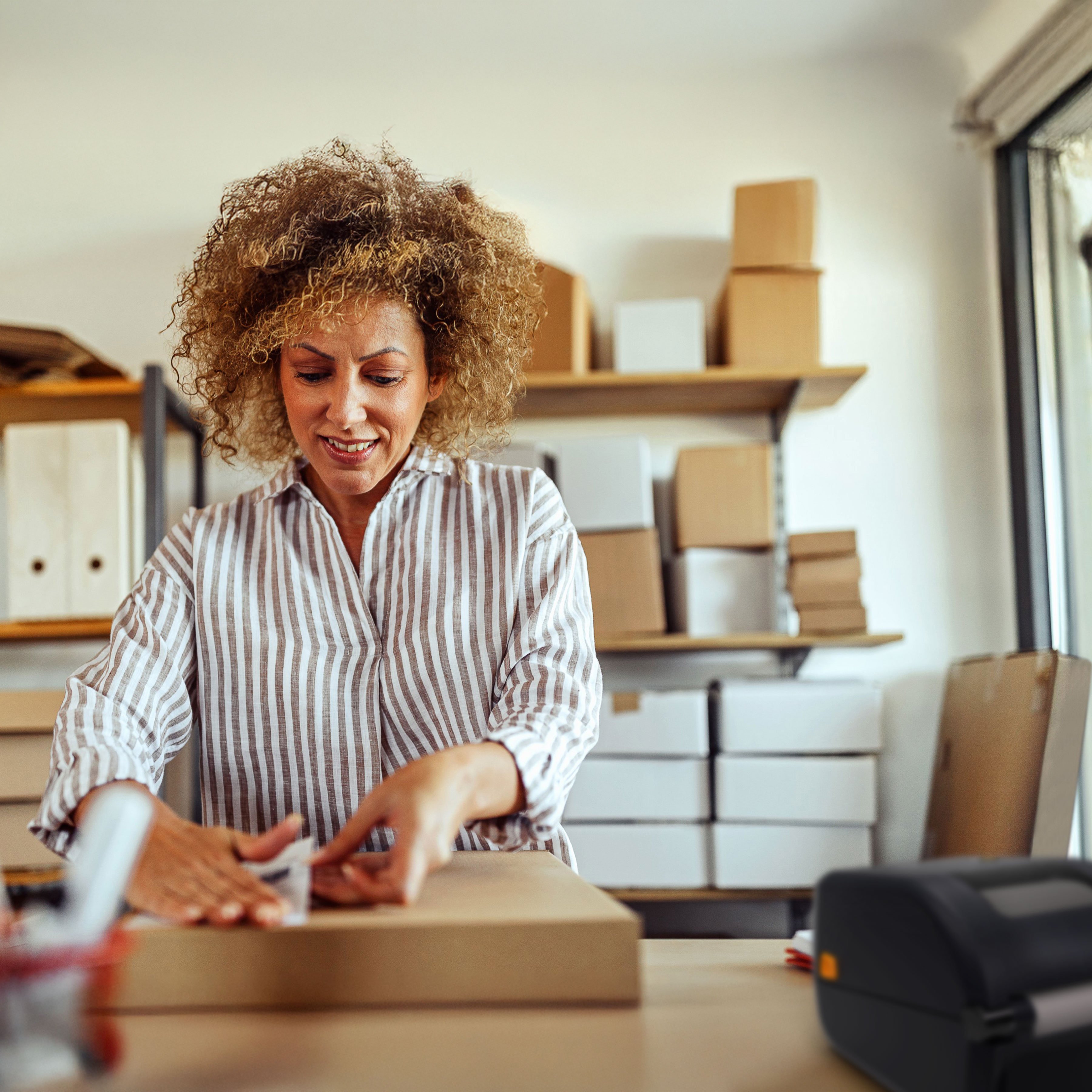 Worker applying a barcode label to a box printed by a Zebra desktop printer.