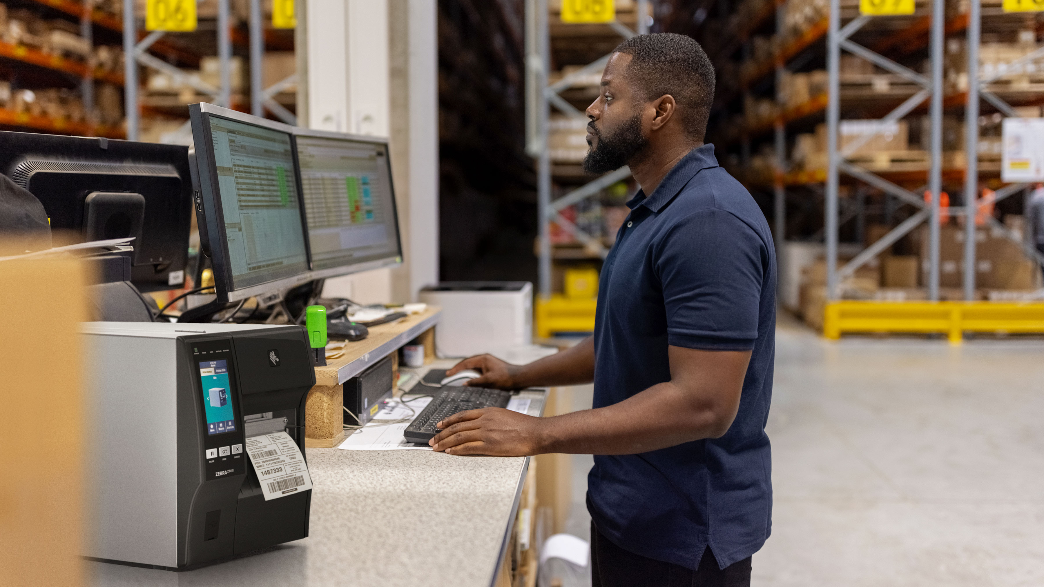 A worker at a computer workstation inside of warehouse facility.