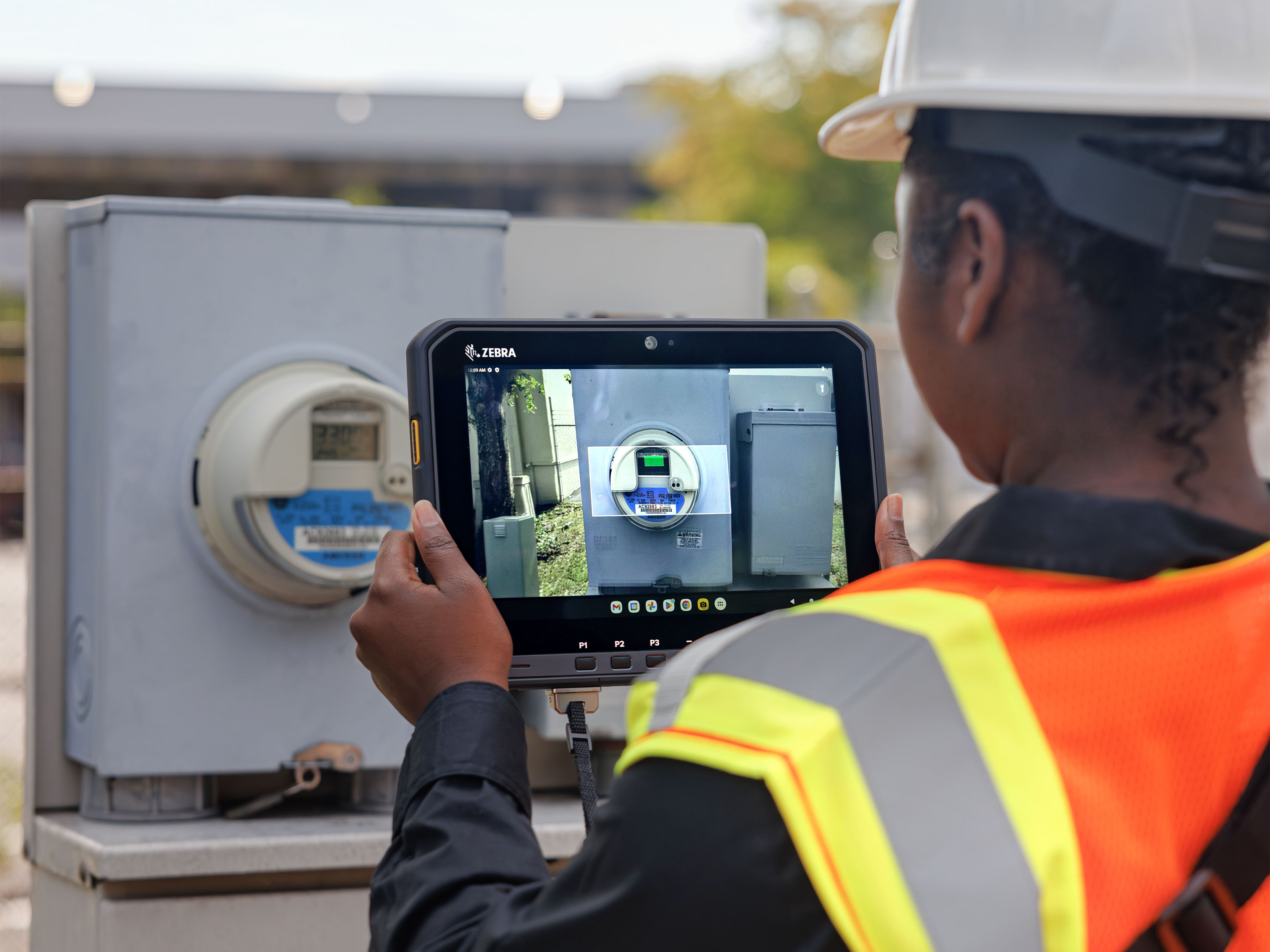 Person in orange safety vest using a ET60 rugged tablet to read a utility meter.
